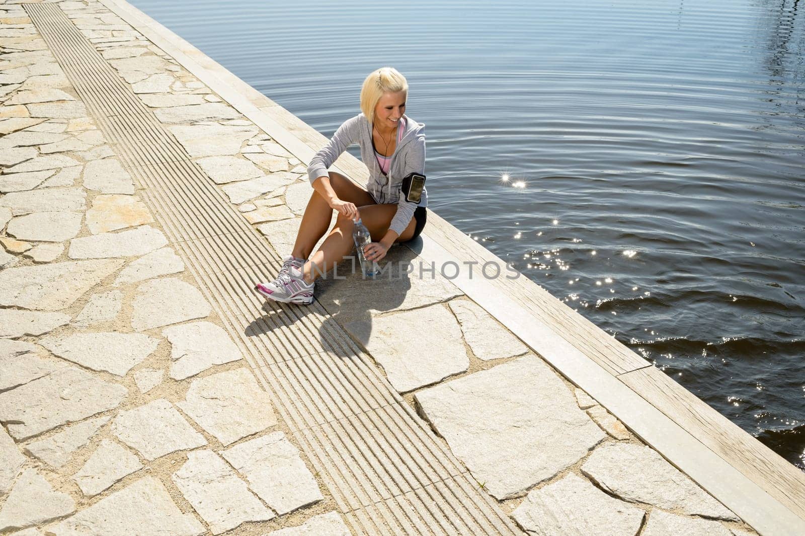 Sport woman relax on pier looking by water summer day