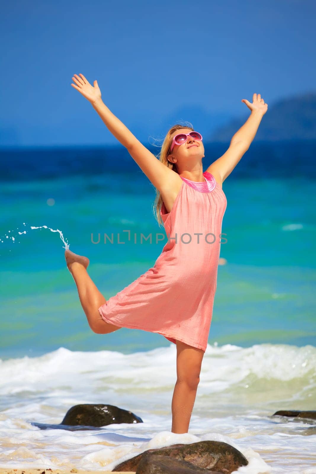 Young woman with hands up at the tropical beach