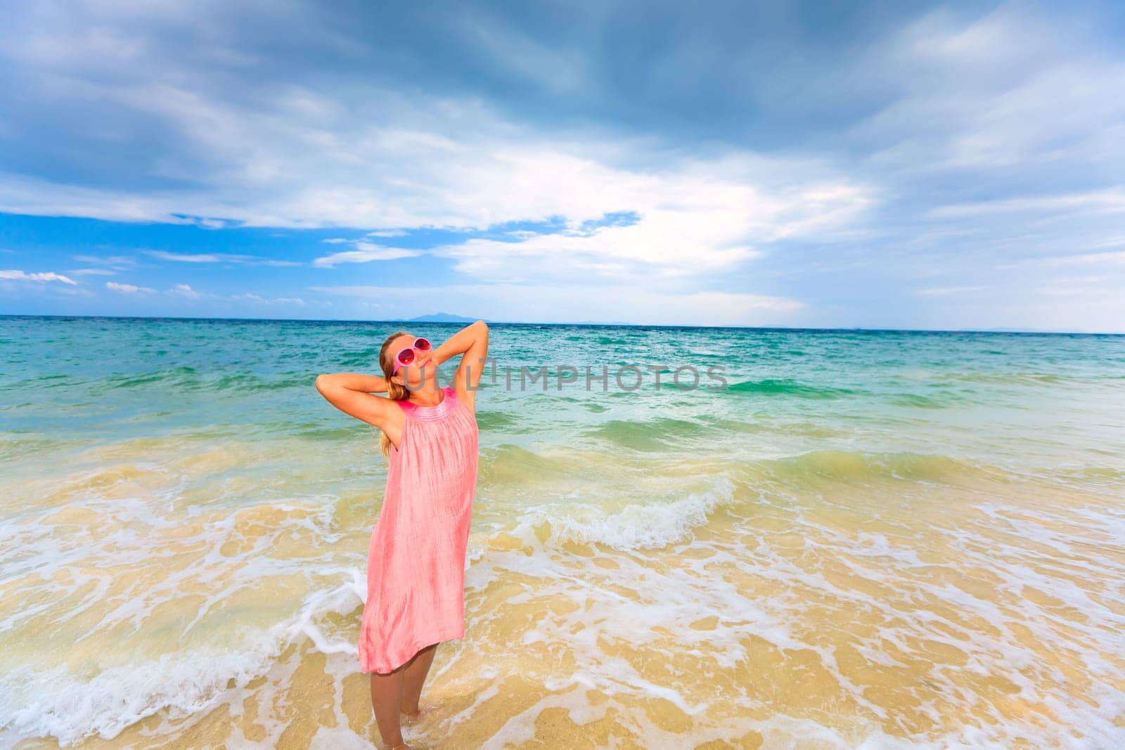 Happy woman with  hands up on the beach