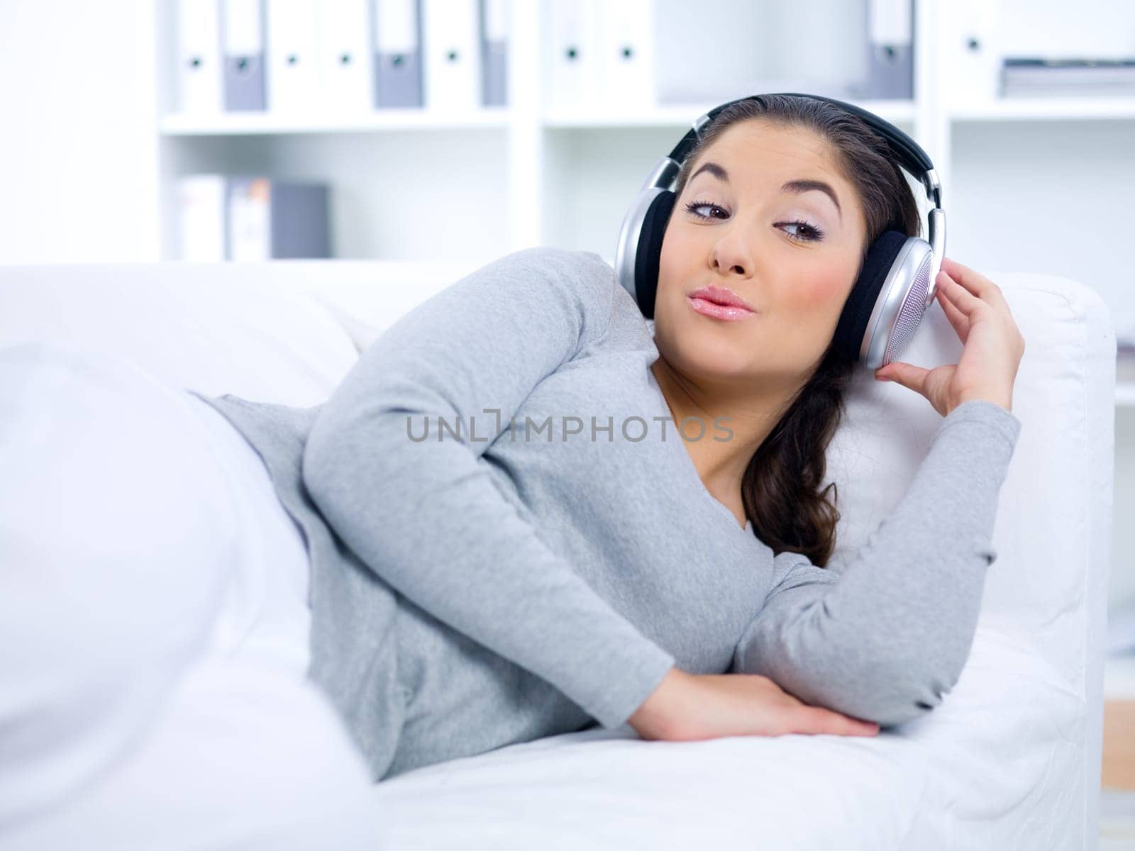Young woman laying on couch and listen to the music