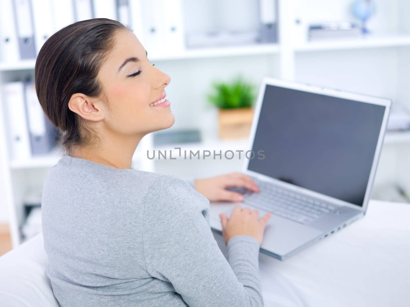 Young woman sitting on couch and working on laptop