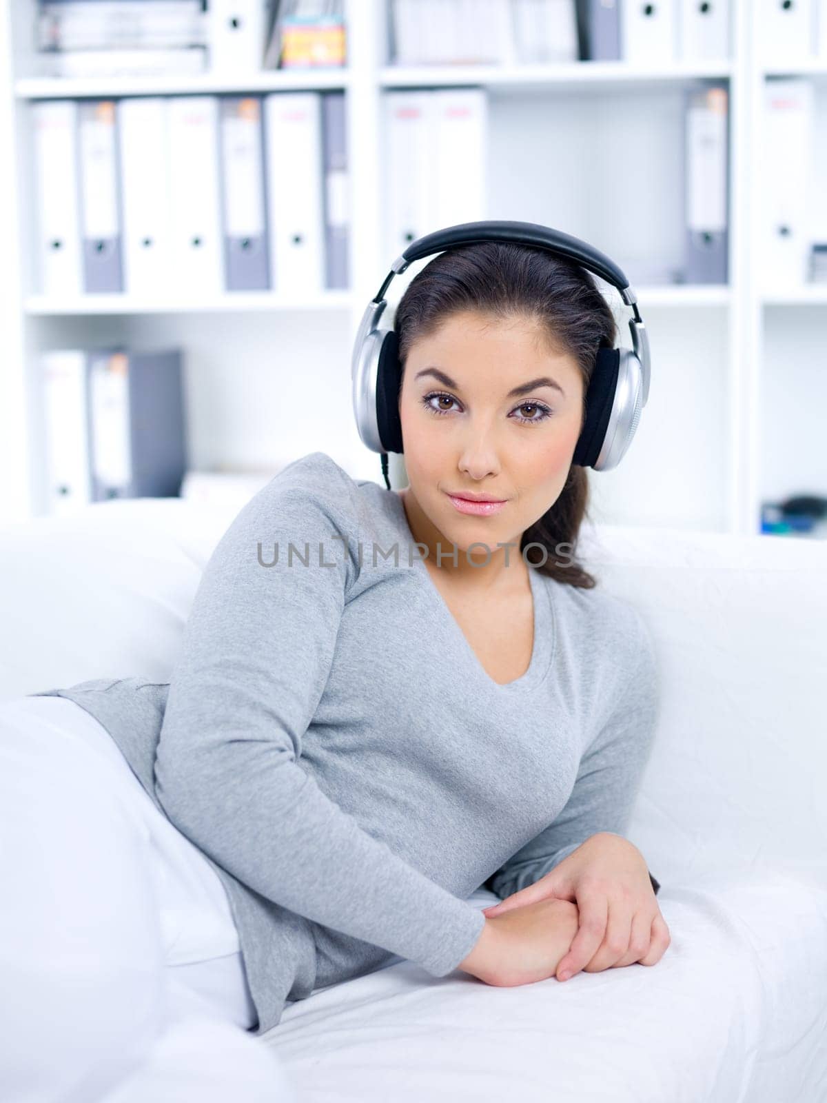 Young woman laying on couch and listen to the music