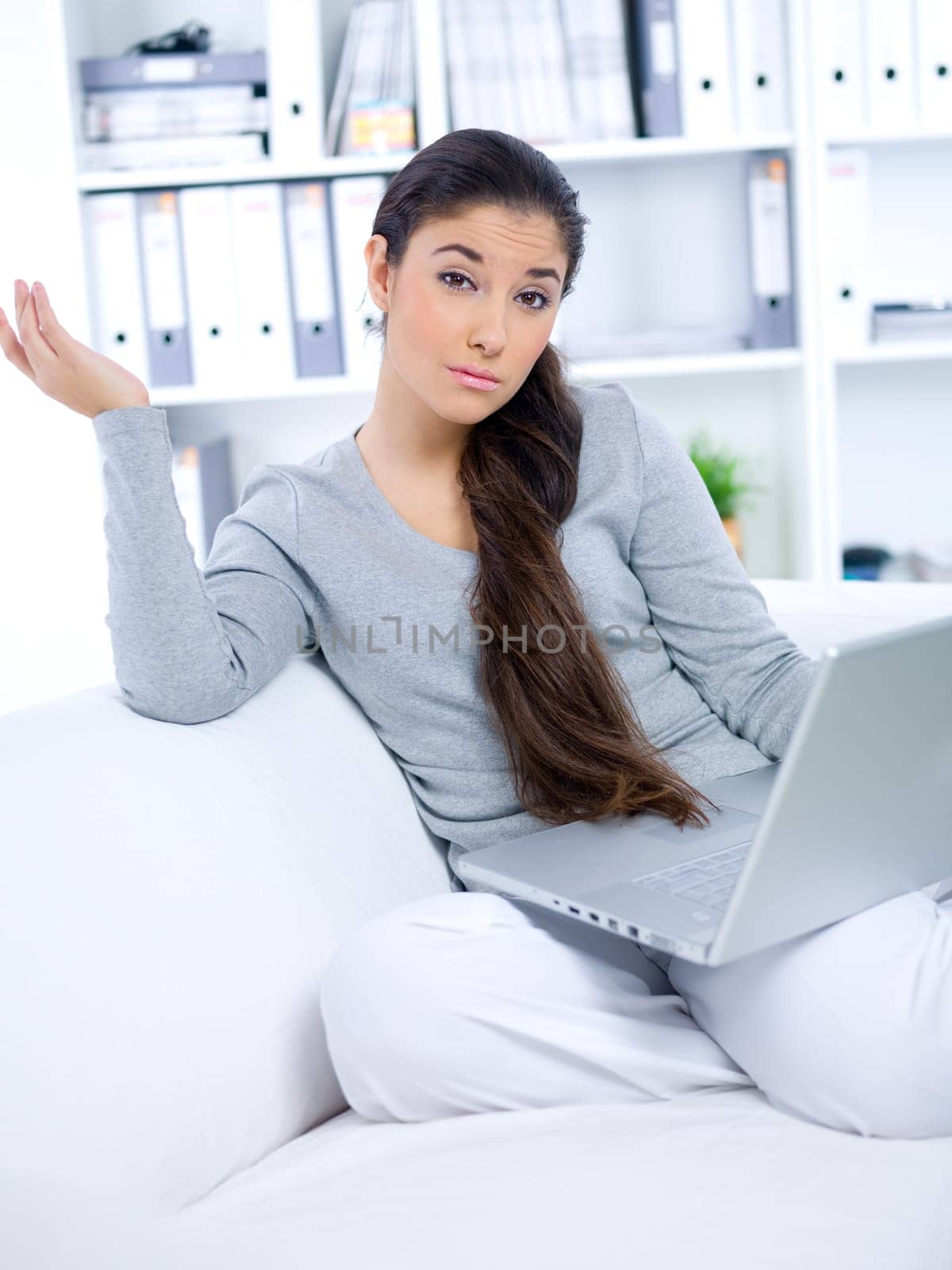 Young woman sitting on couch and working on laptop