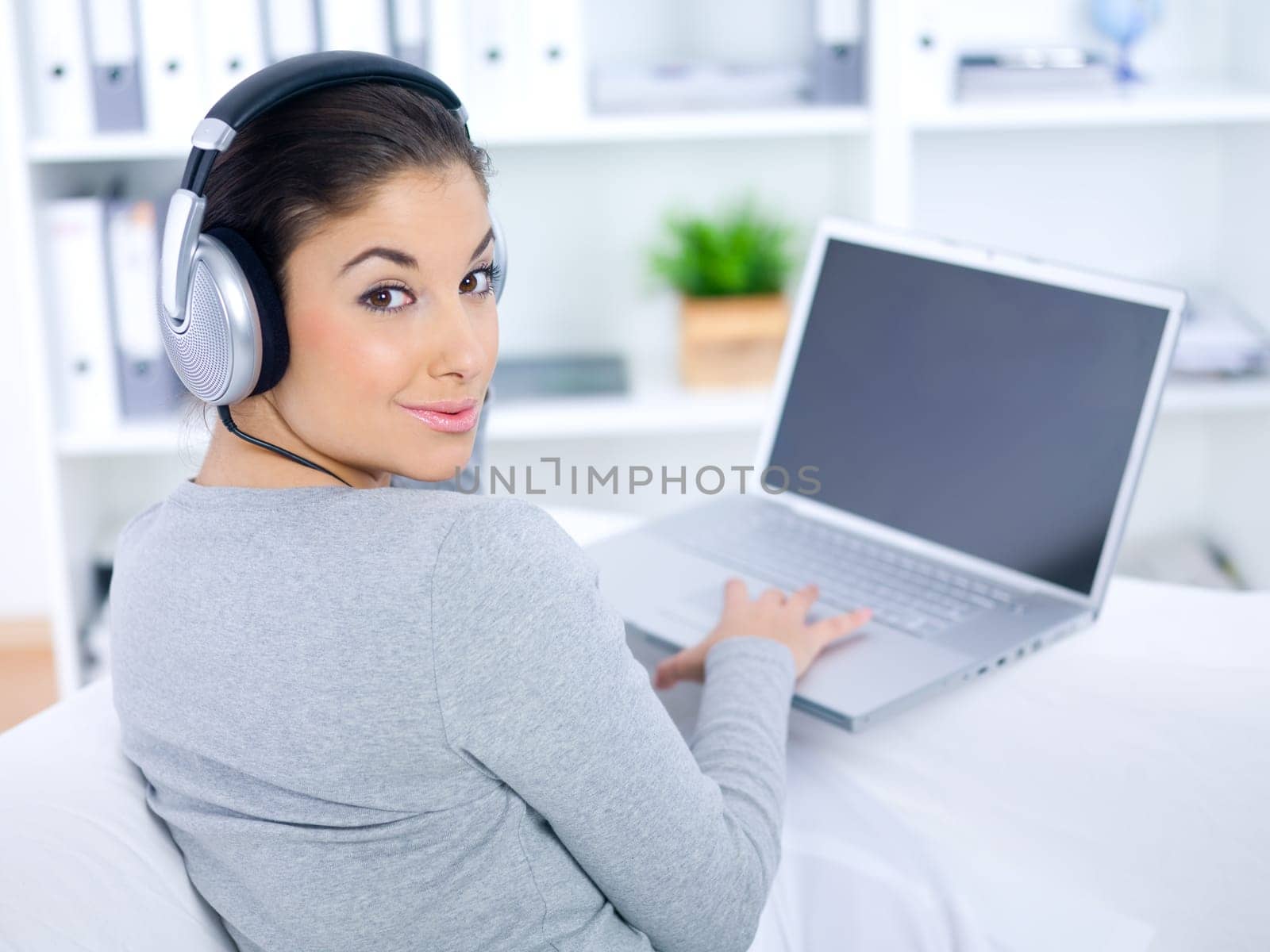 Young woman sitting on couch and working on laptop