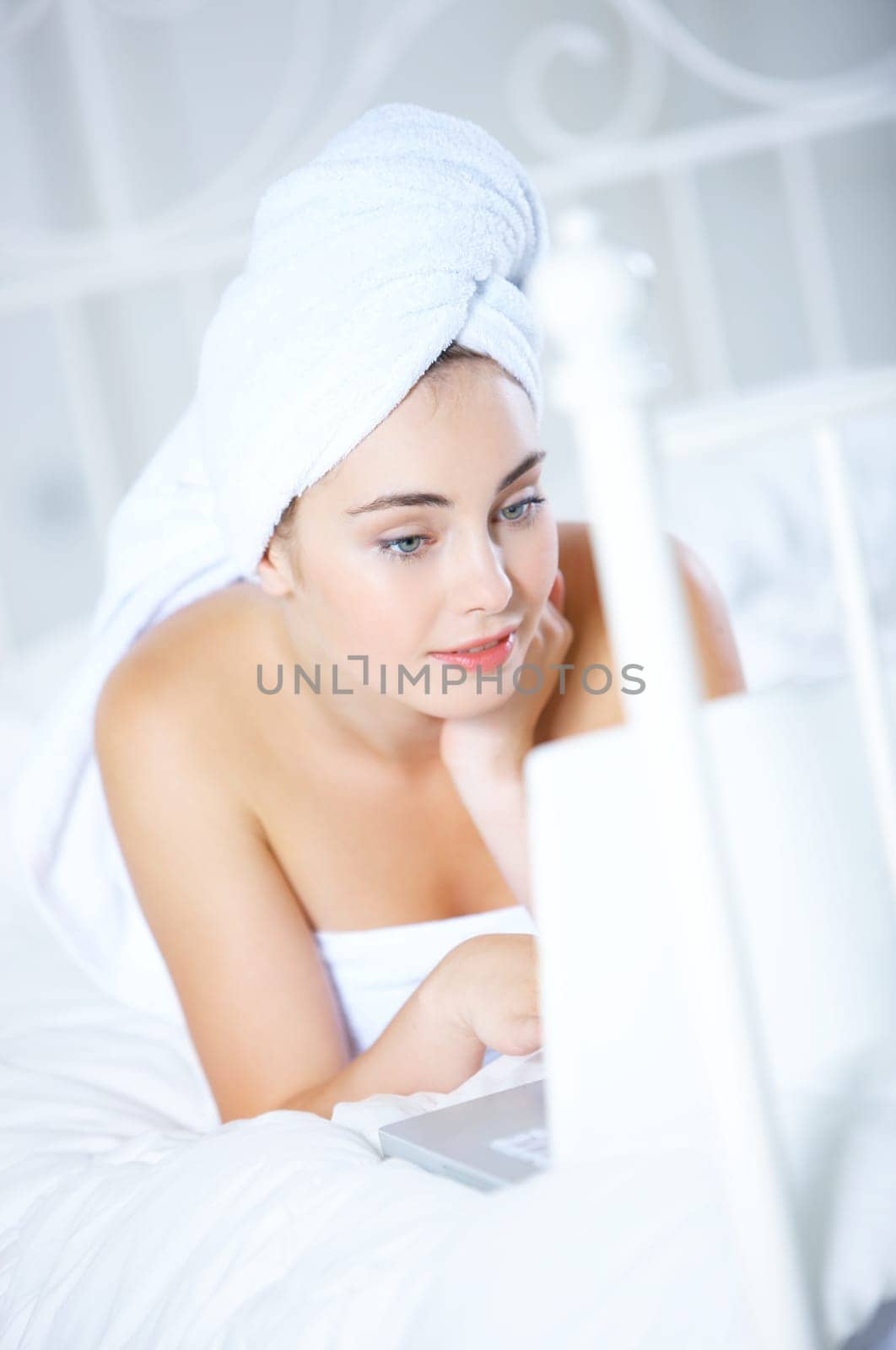 Portrait of cute teenage girl on white bed with laptop