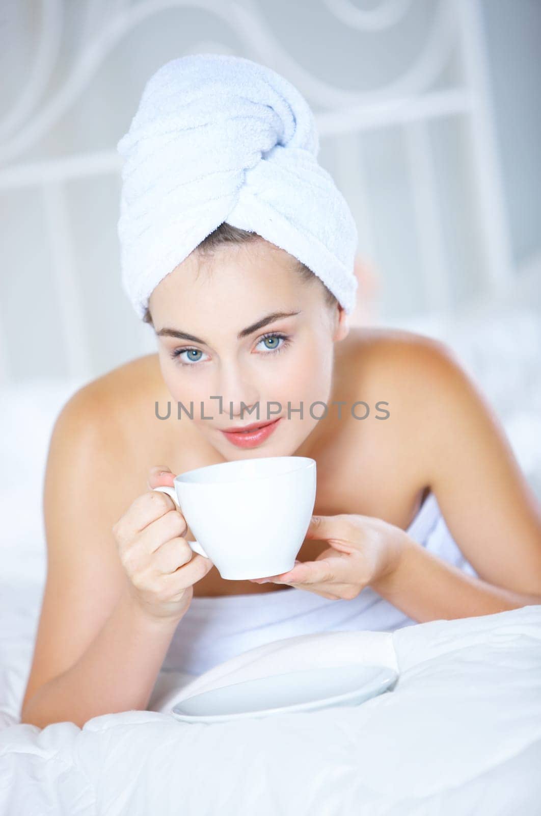 Portrait of cute teenage girl lying on white bed