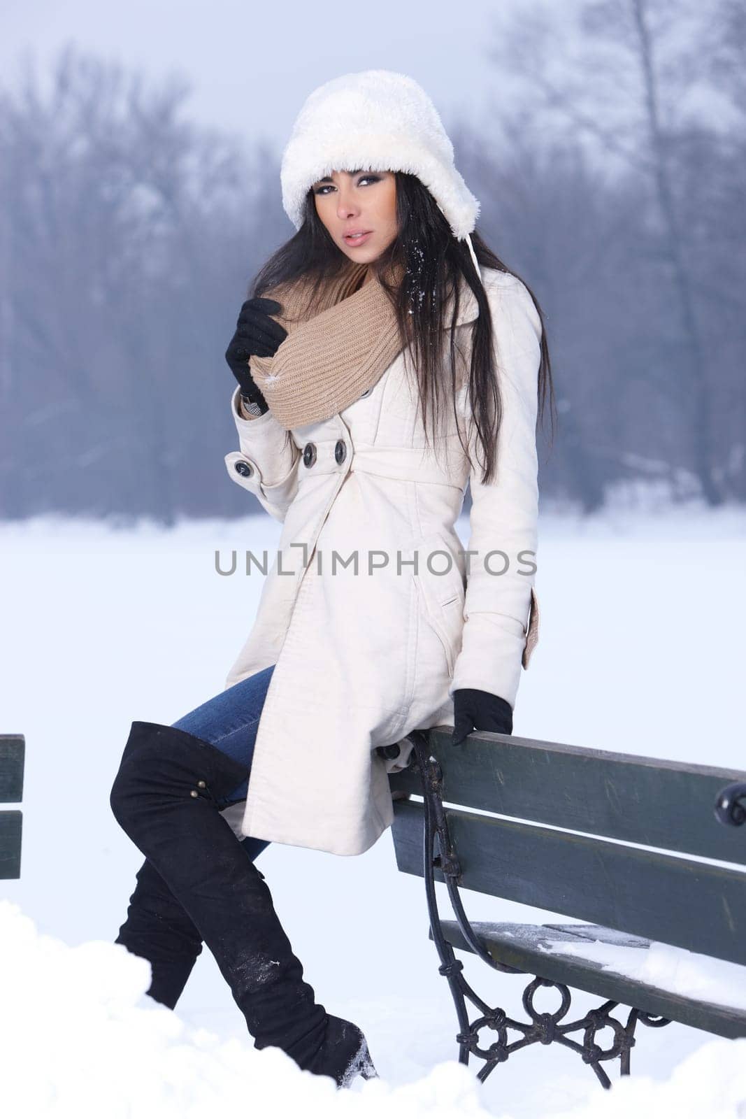 Beautiful and sexy woman sitting on bench in snowy outdoors