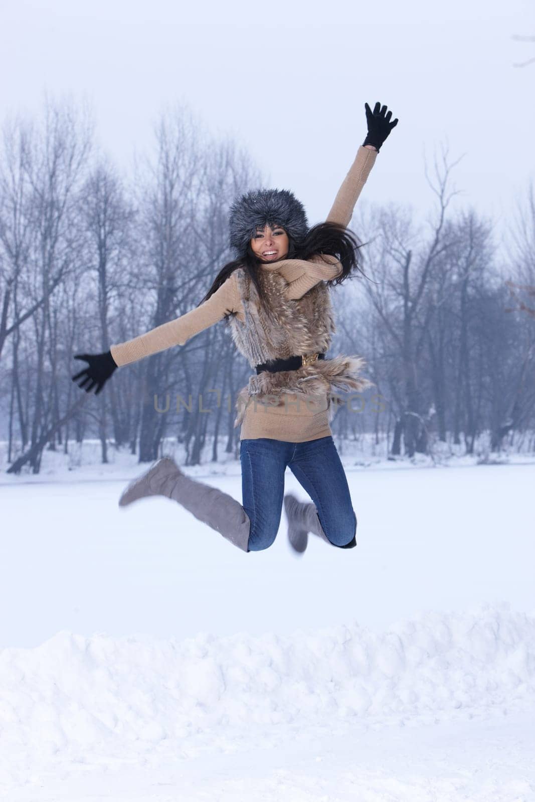 Young Jumping woman in snowy winter outdoors