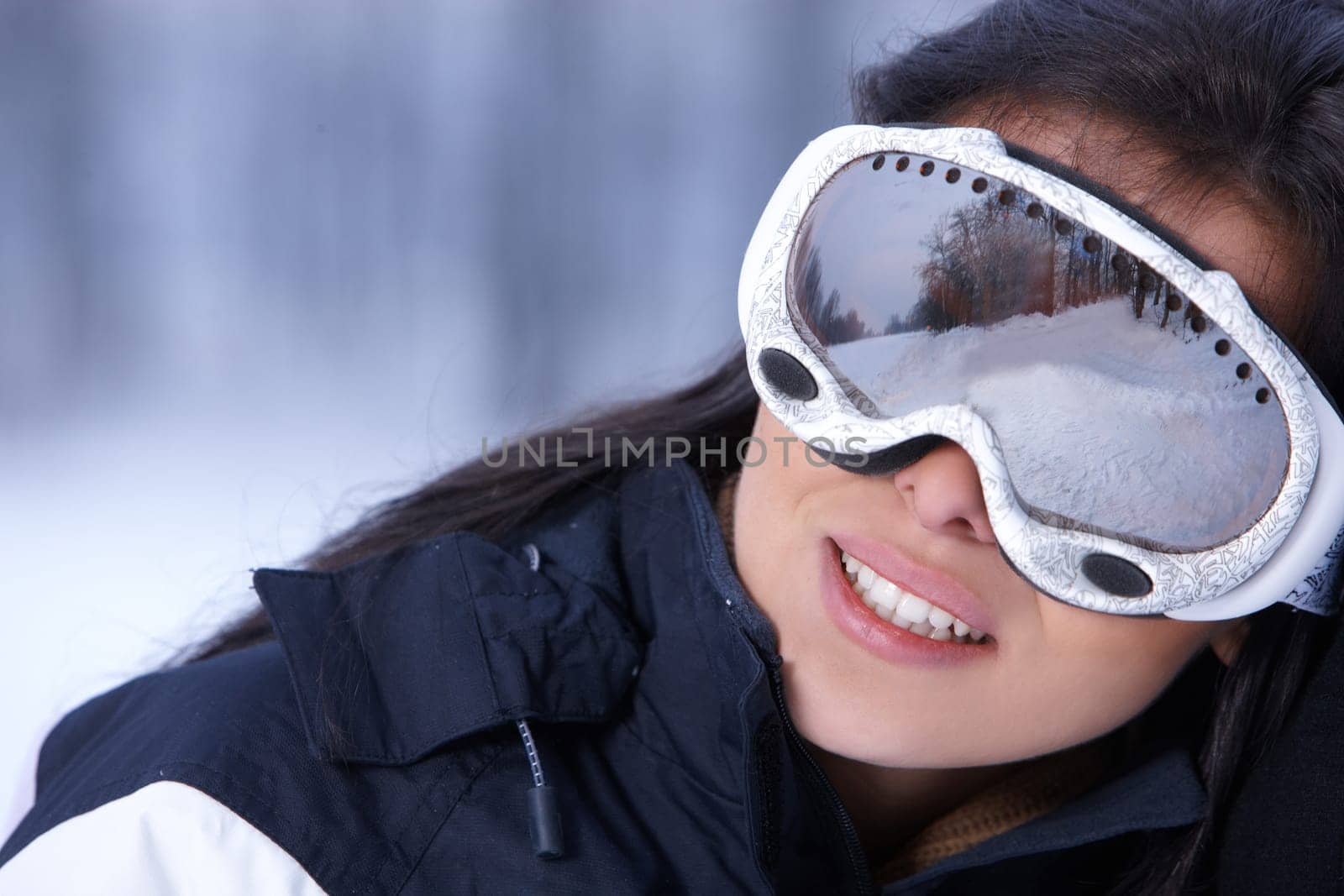 Beautiful woman wearing goggles in snowy winter outdoors