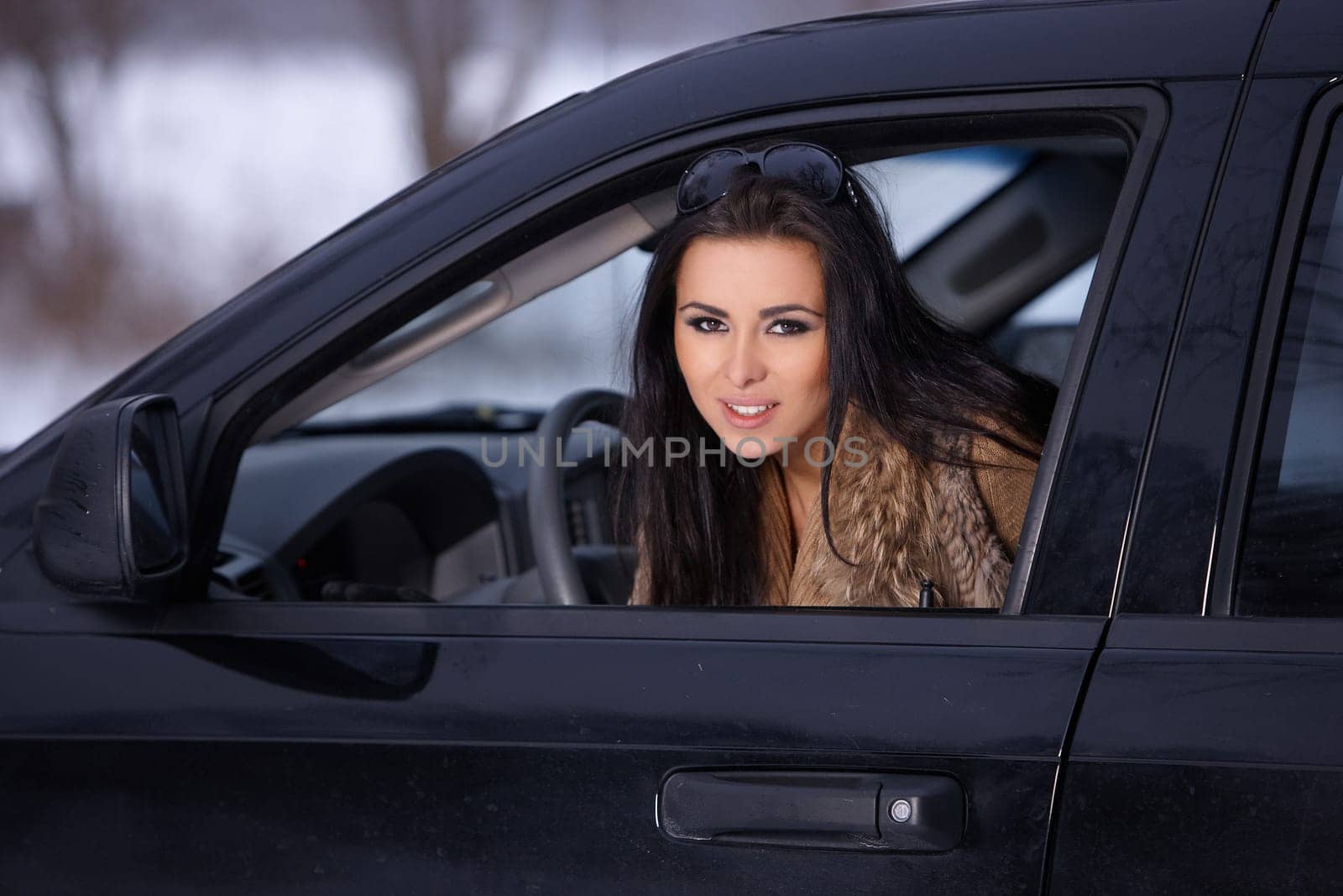 Beautiful woman in car in snowy winter outdoors