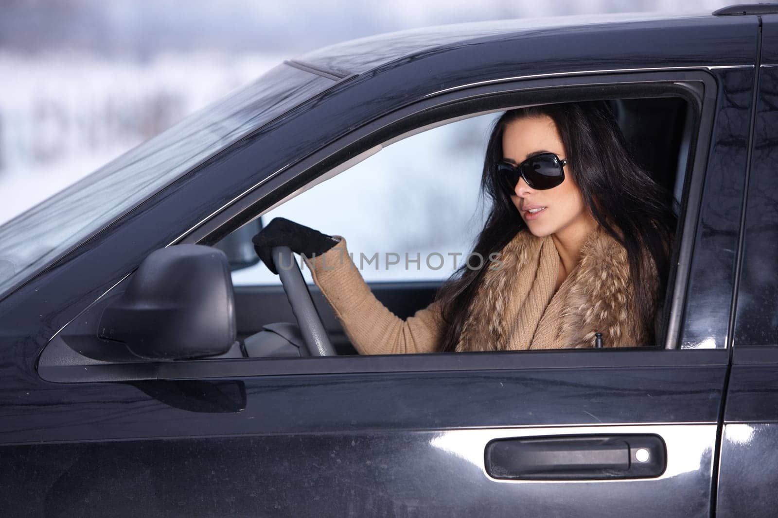 Beautiful woman in car in snowy winter outdoors