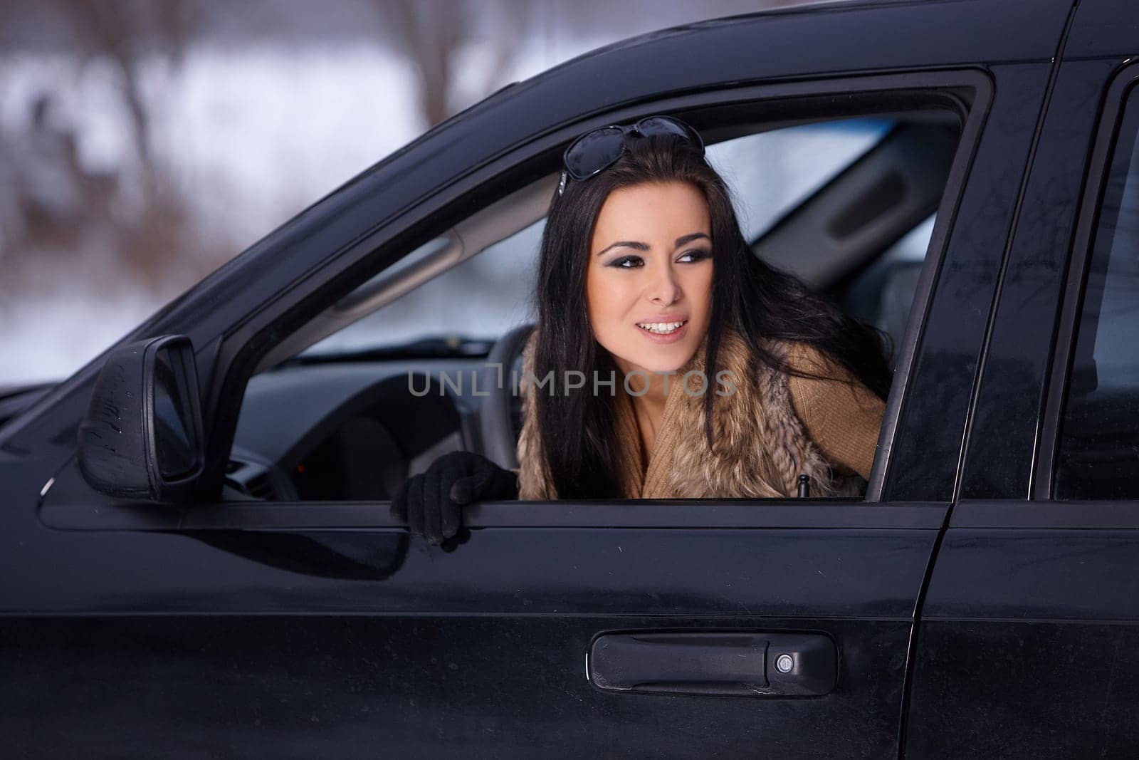 Beautiful woman in car in snowy winter outdoors