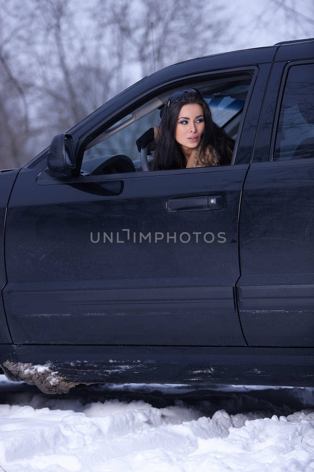 Beautiful woman in car in snowy winter outdoors
