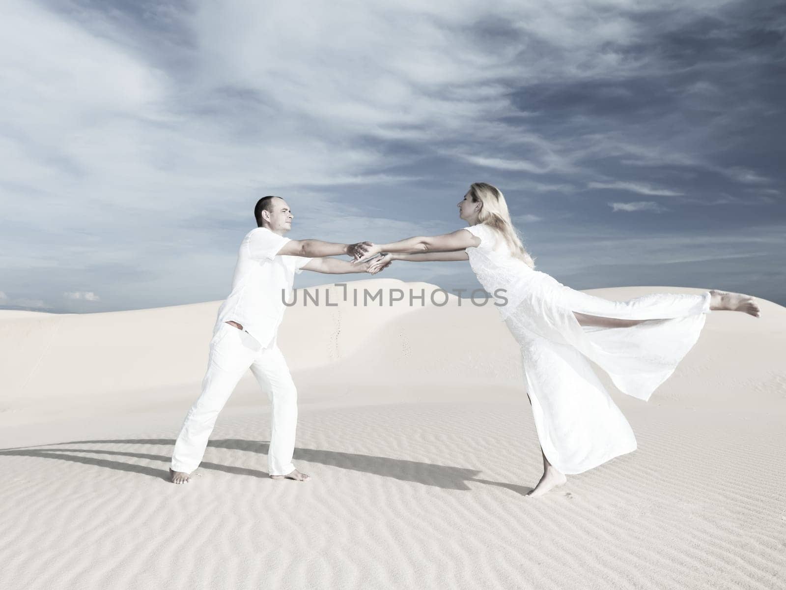 Young couple dancing on desert dune at wedding date