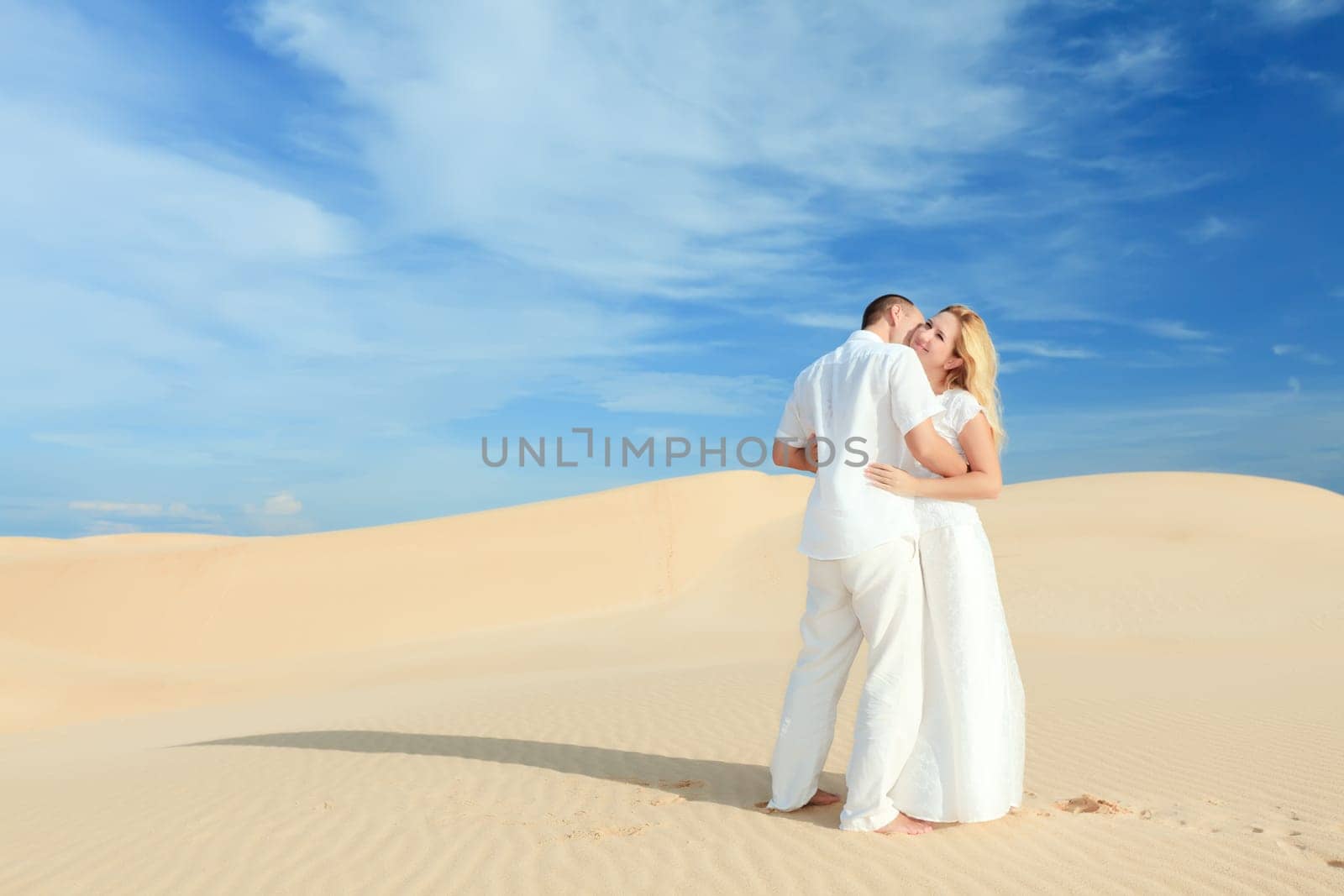 Young couple on desert dunes in white