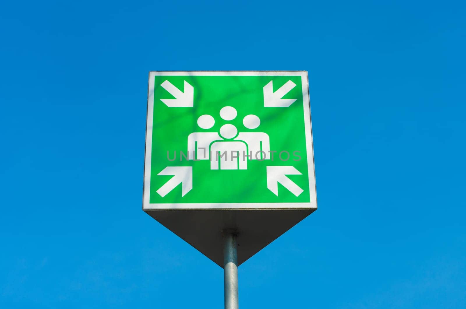 emergency assembly point green sign against a blue sky