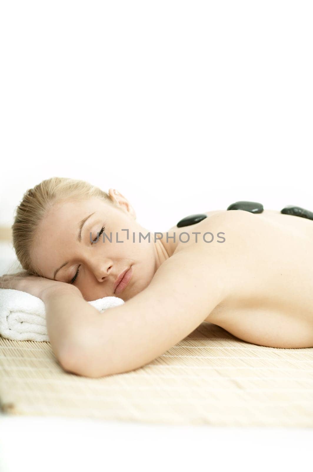 Young blond woman getting lastone treatment at spa