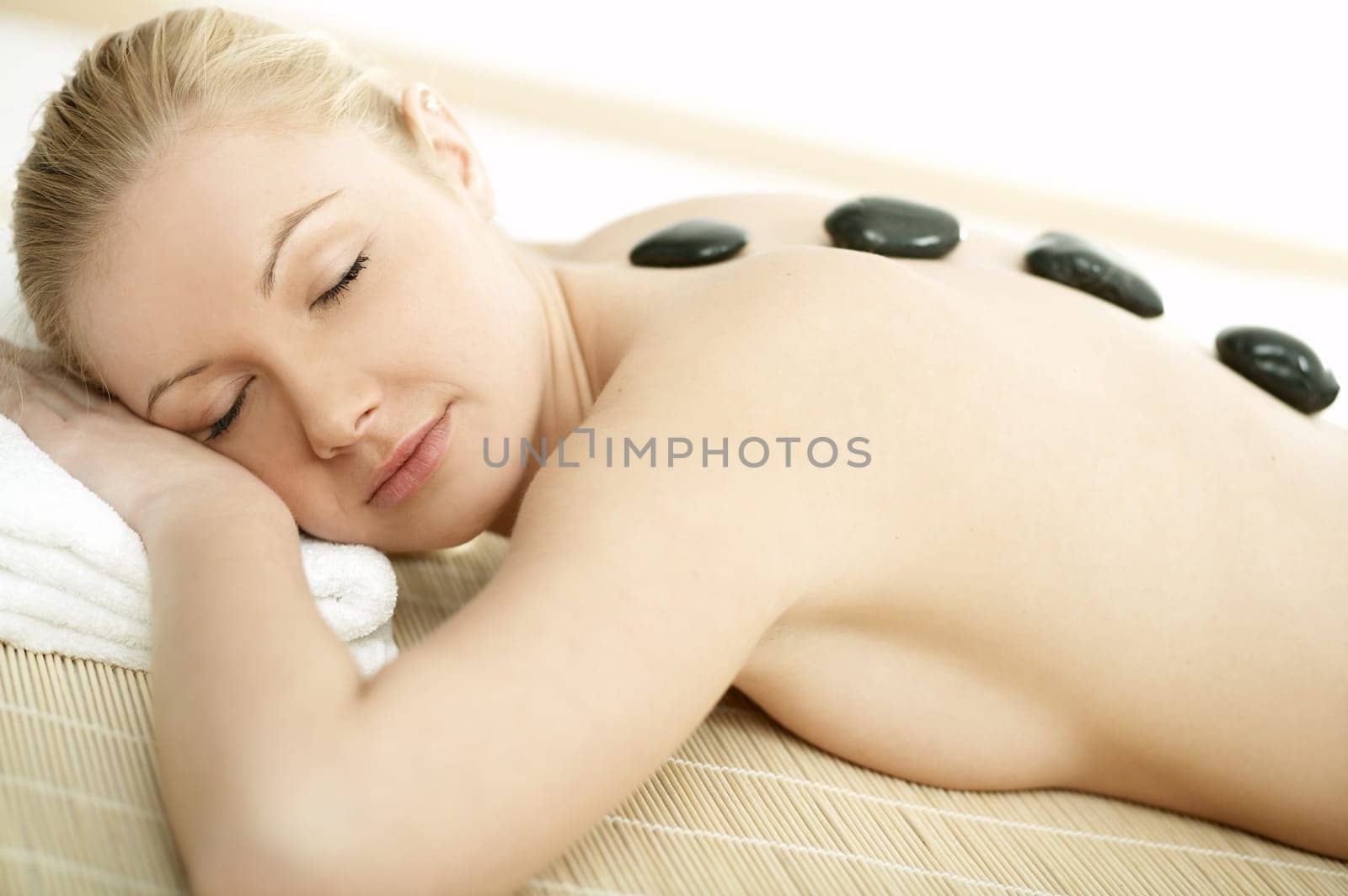 Young blond woman getting lastone treatment at spa