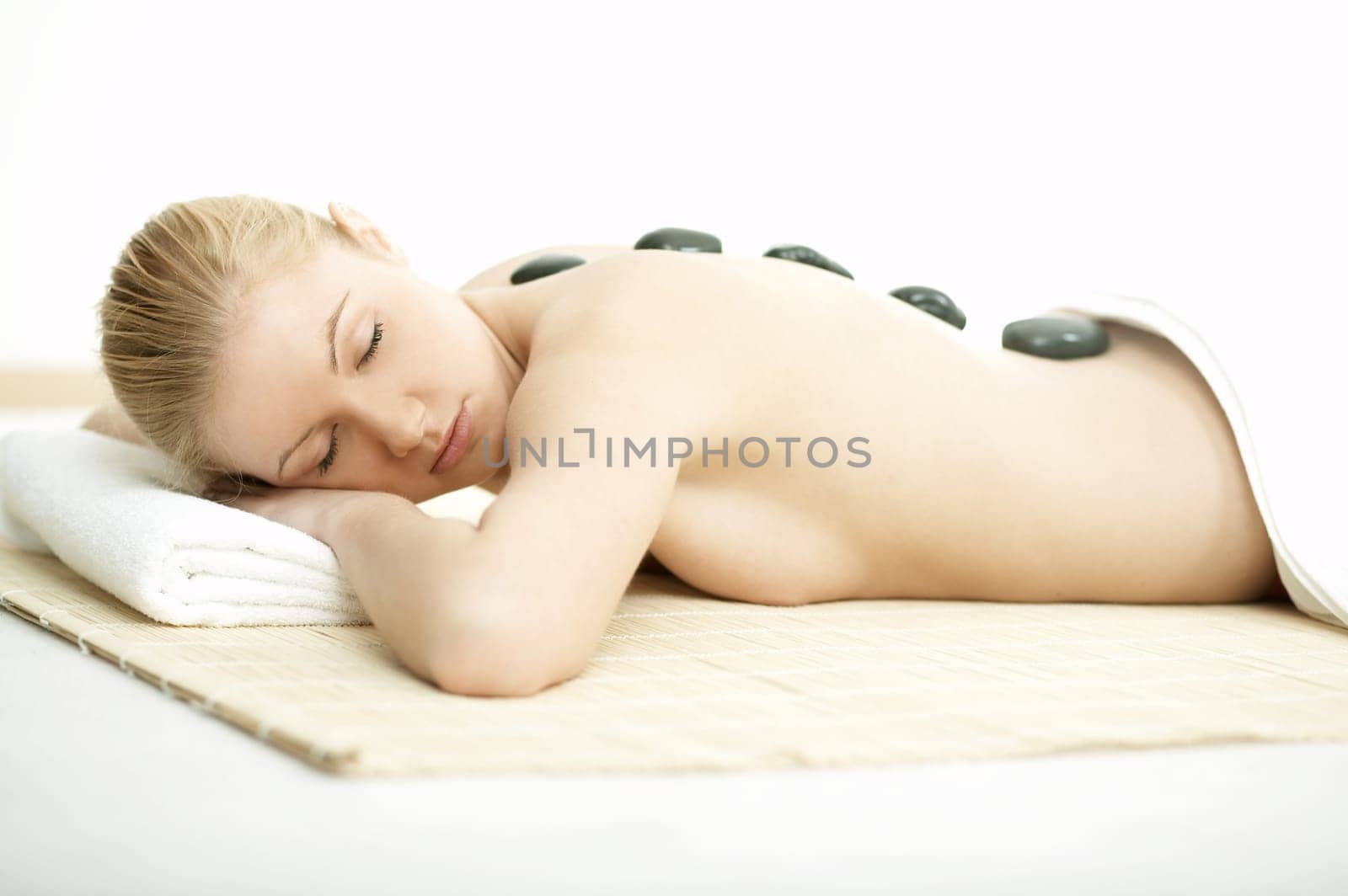 Young blond woman getting lastone treatment at spa