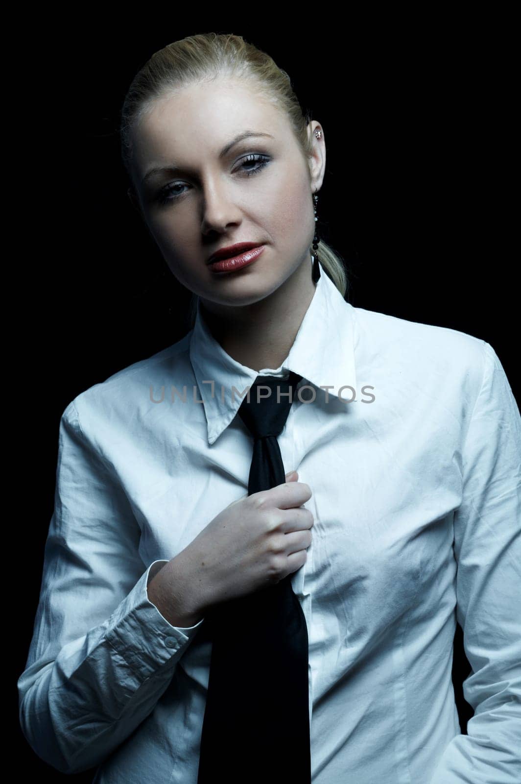 Beautiful business woman wearing black tie and white shirt isolated on black background