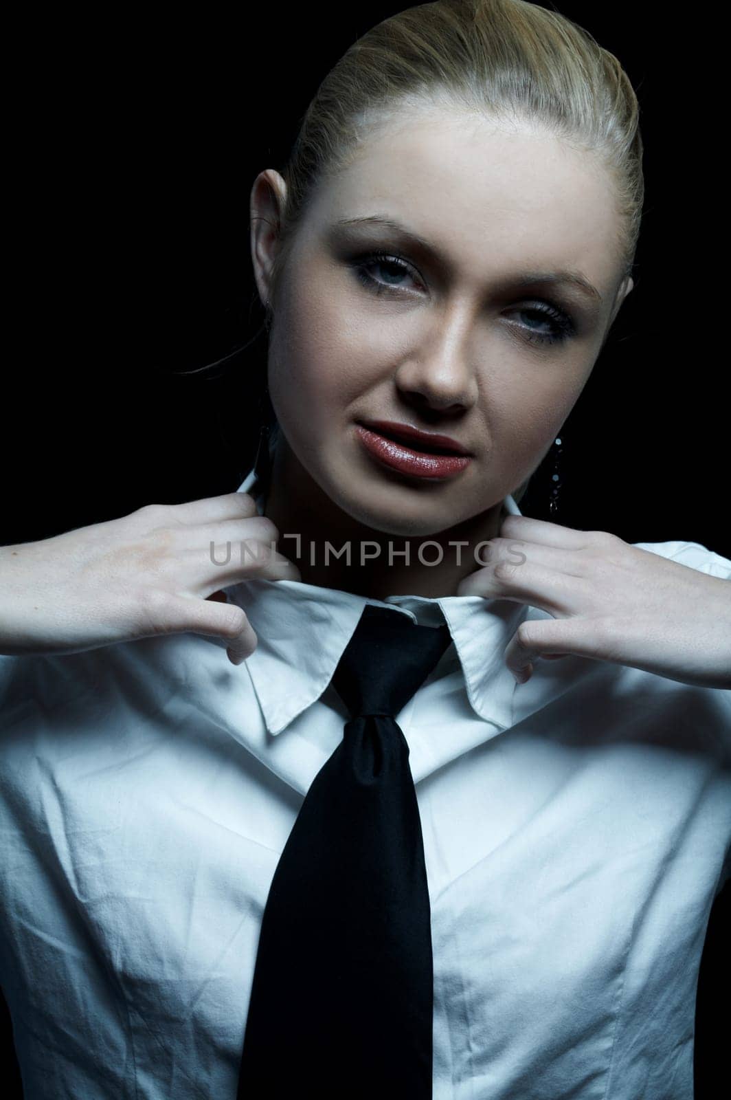 Beautiful business woman wearing black tie and white shirt isolated on black background