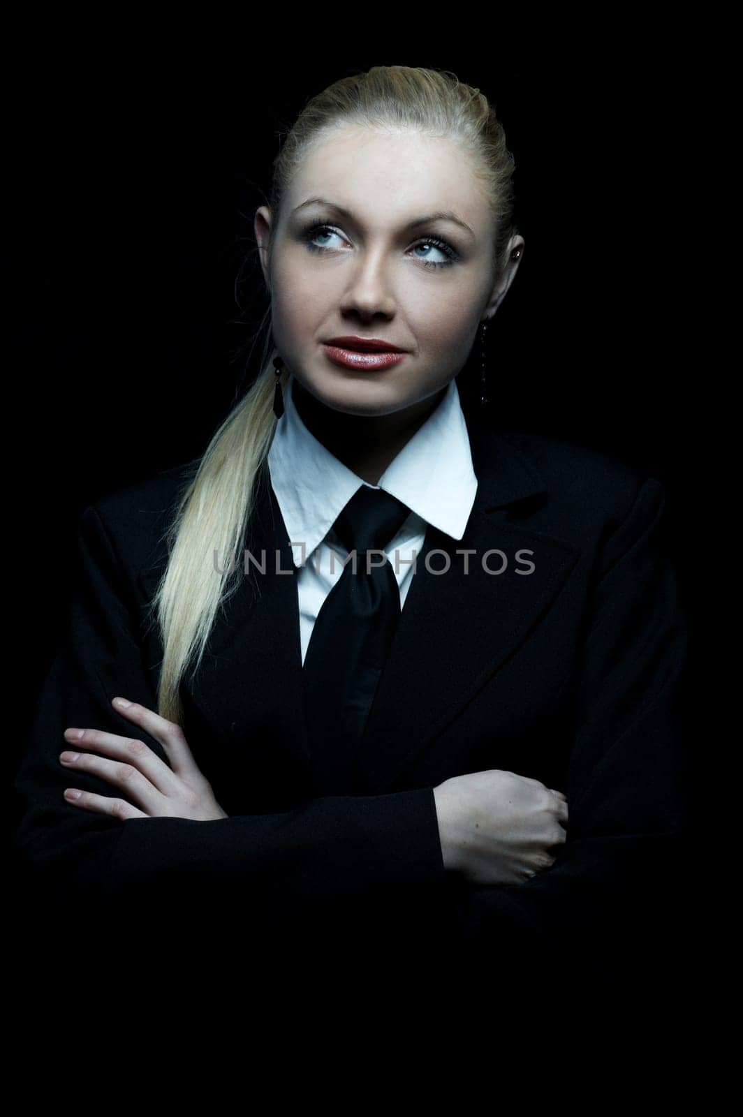 Beautiful business woman wearing black tie and jacket isolated on black background