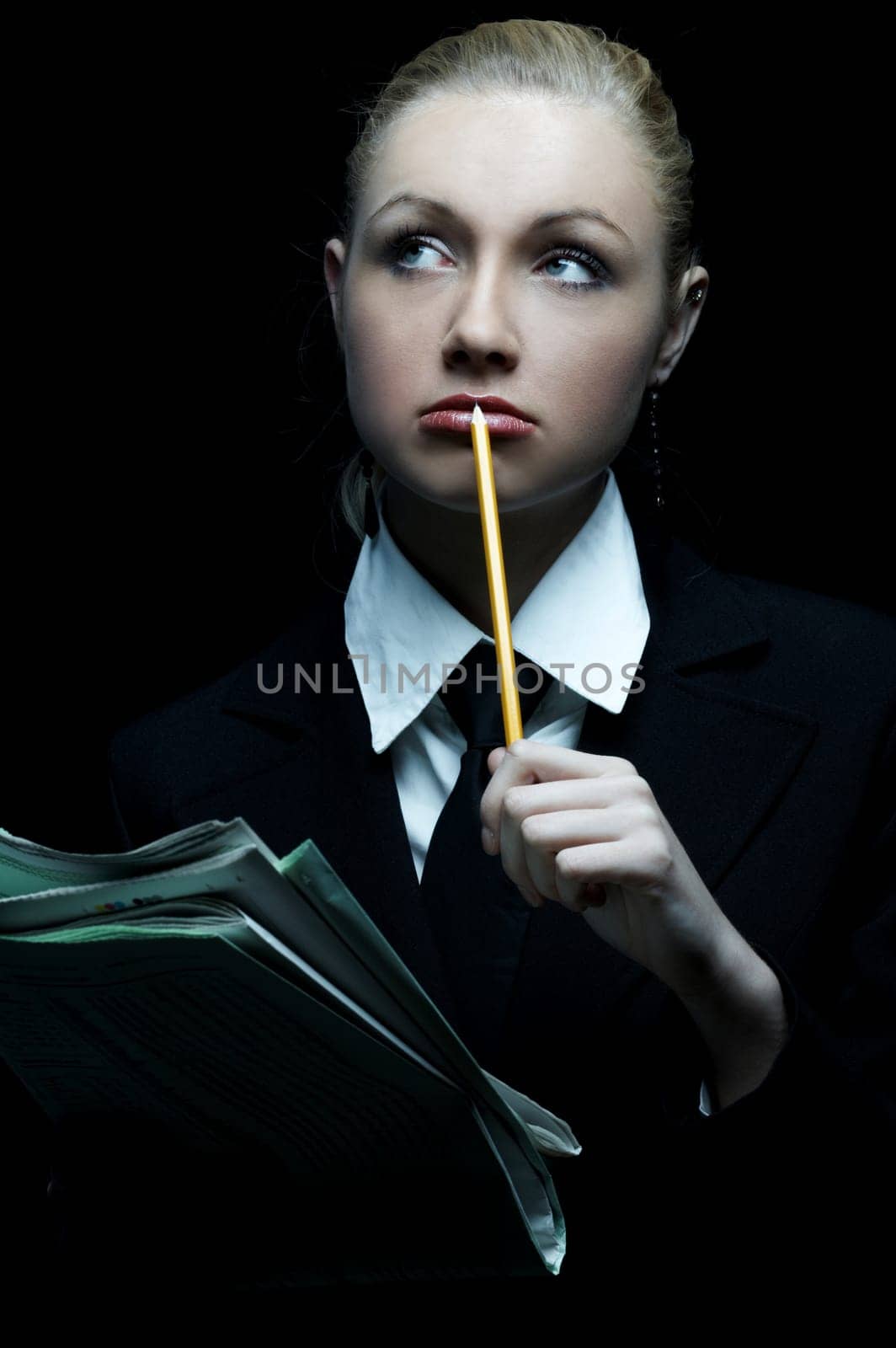 Beautiful business woman wearing black tie and jacket isolated on black background holding newspaper