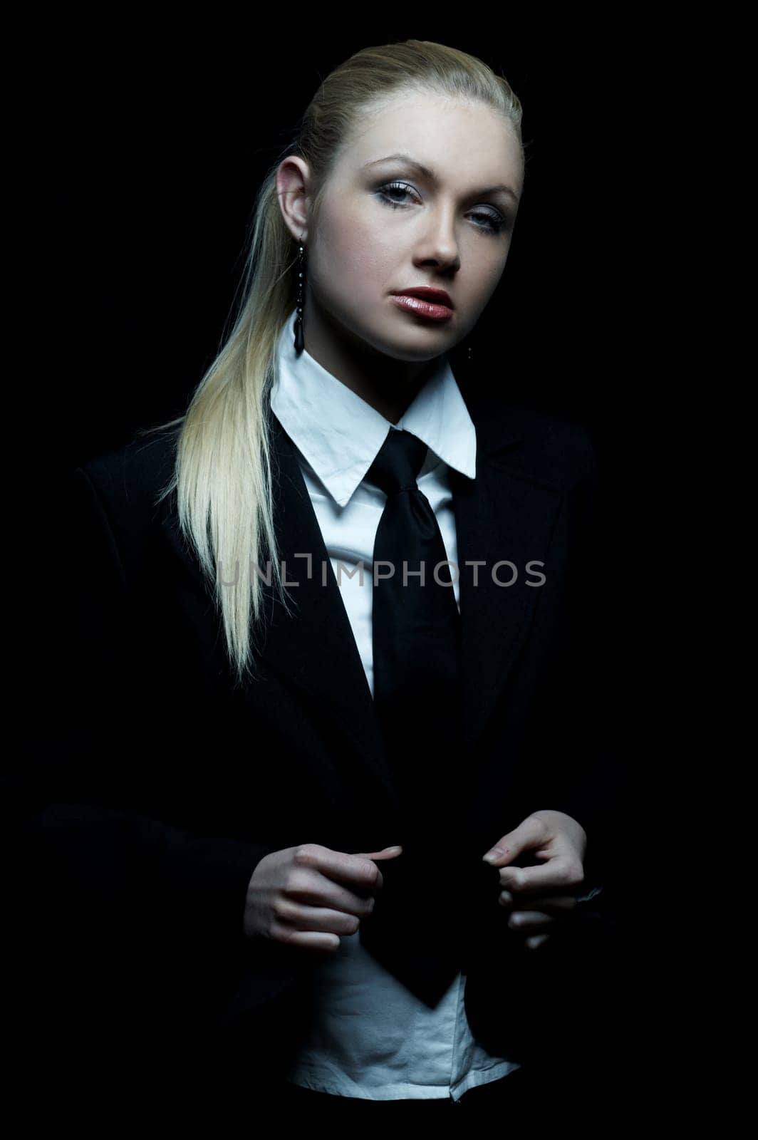 Beautiful business woman wearing black tie and jacket isolated on black background