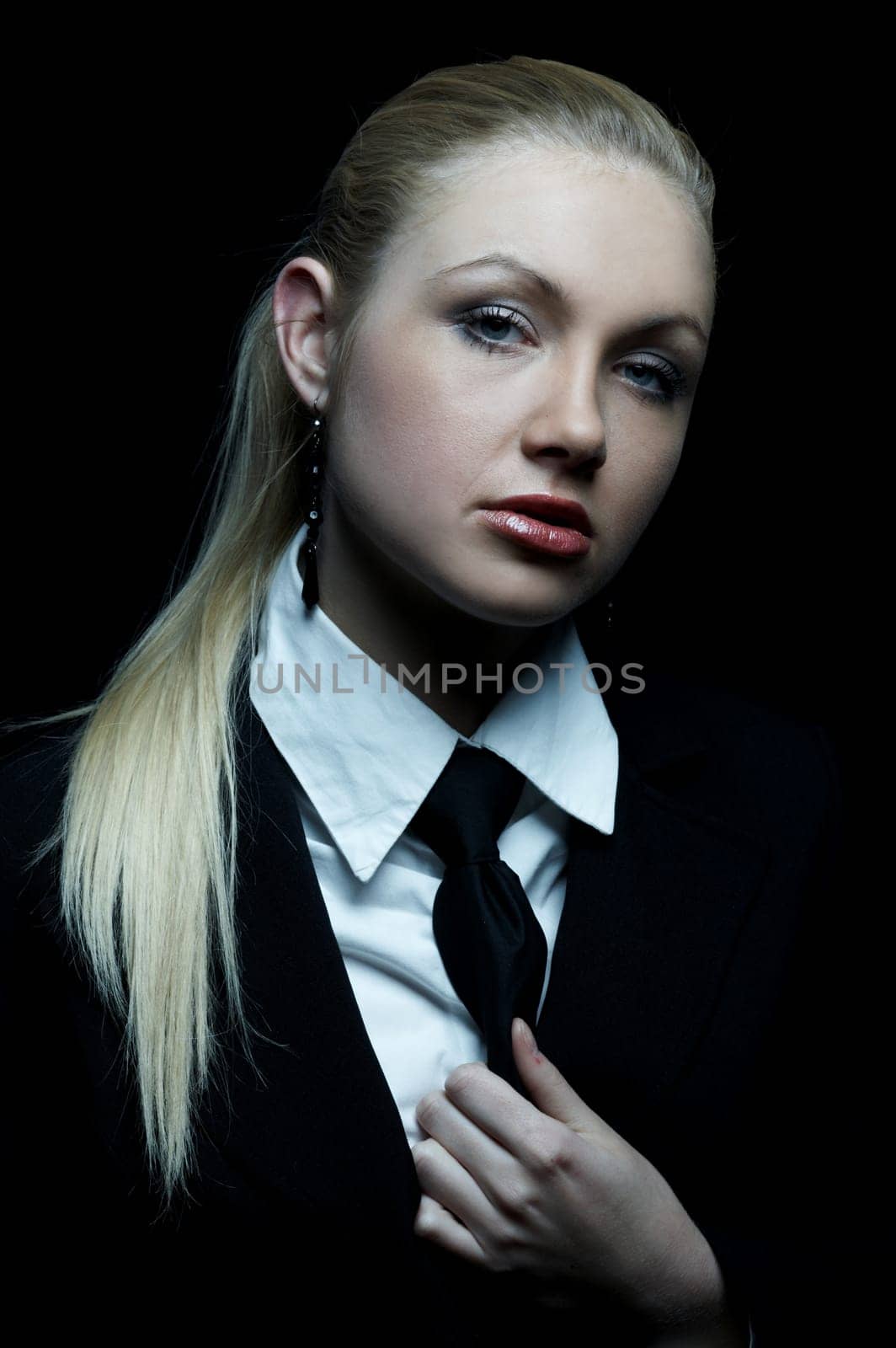 Beautiful business woman wearing black tie and jacket isolated on black background