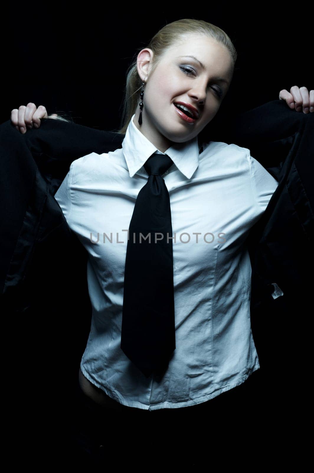 Beautiful business woman wearing black tie and jacket isolated on black background