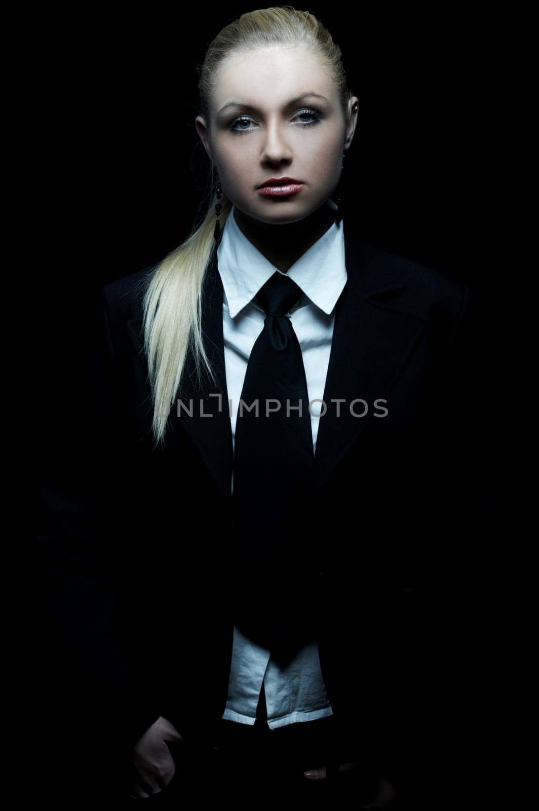 Beautiful business woman wearing black tie and jacket isolated on black background