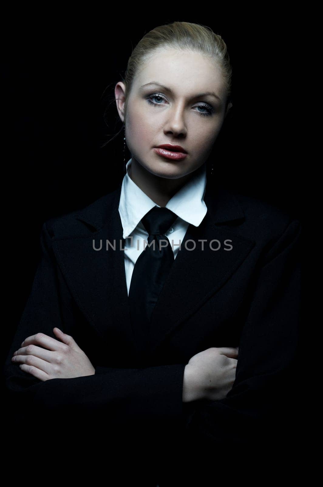Beautiful business woman wearing black tie and jacket isolated on black background