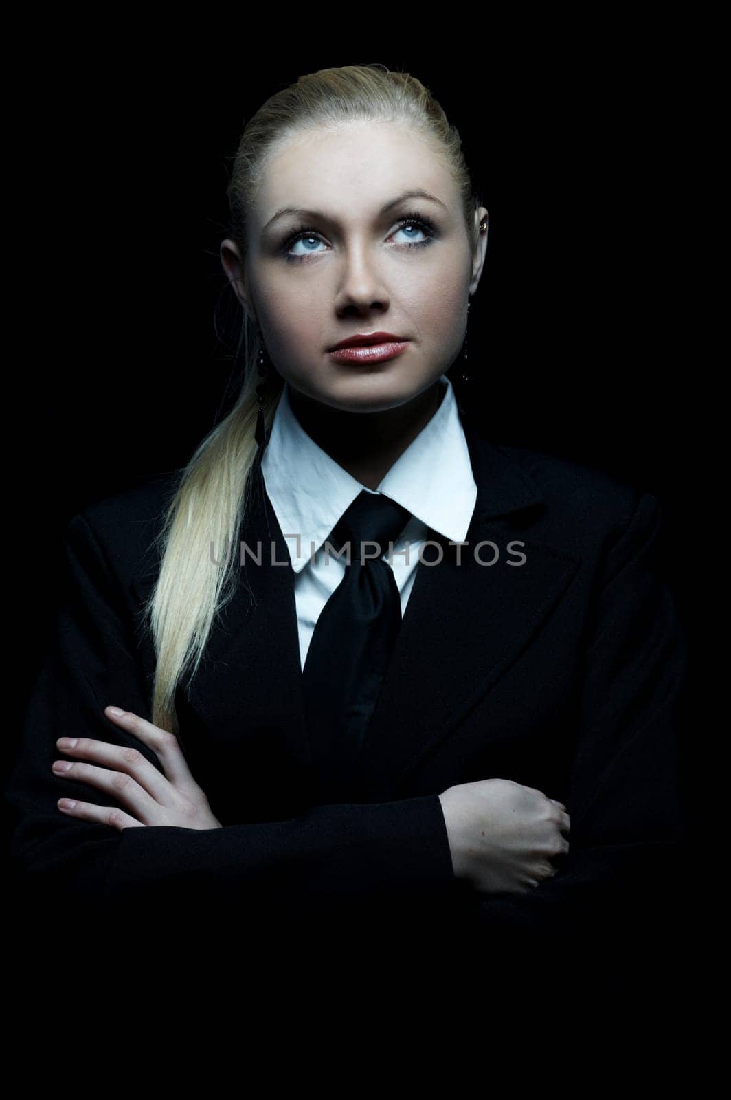 Beautiful business woman wearing black tie and jacket isolated on black background