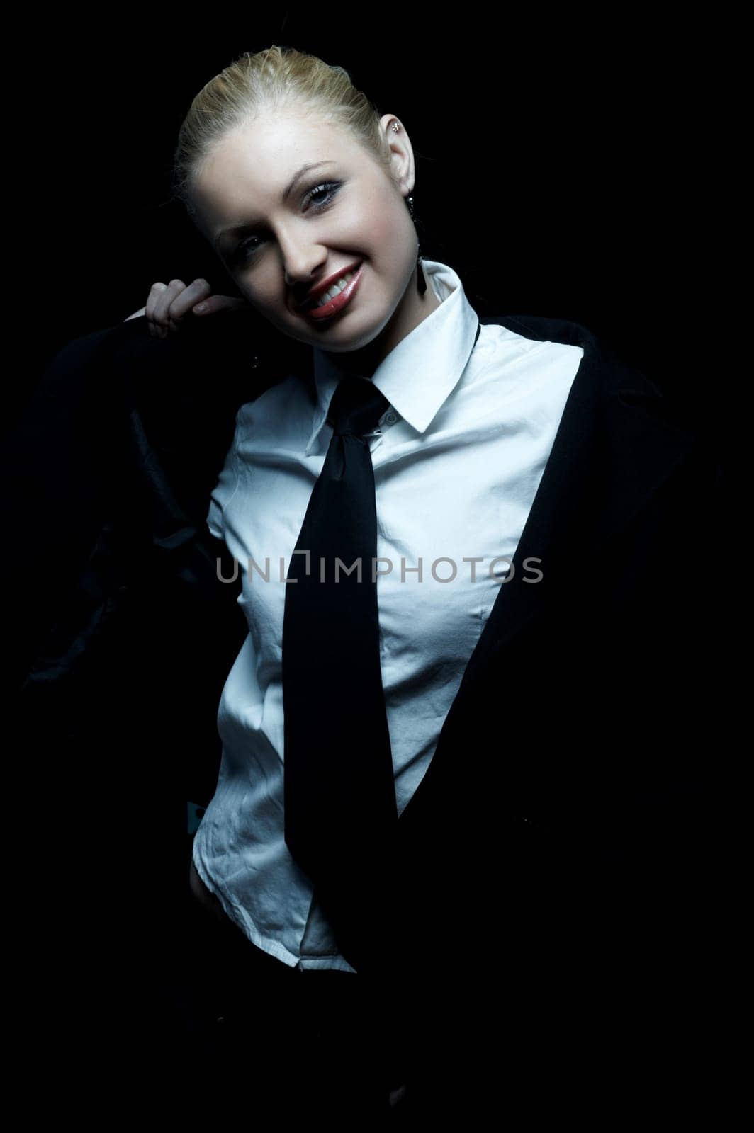 Beautiful business woman wearing black tie and jacket isolated on black background