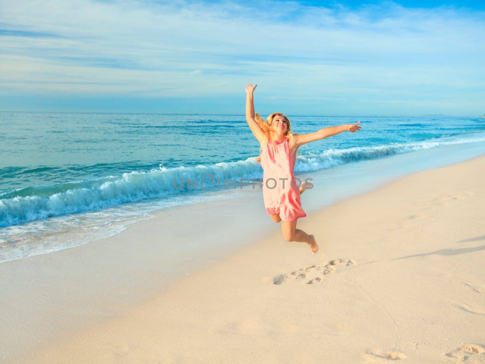 Woman jumping at a white sand beach