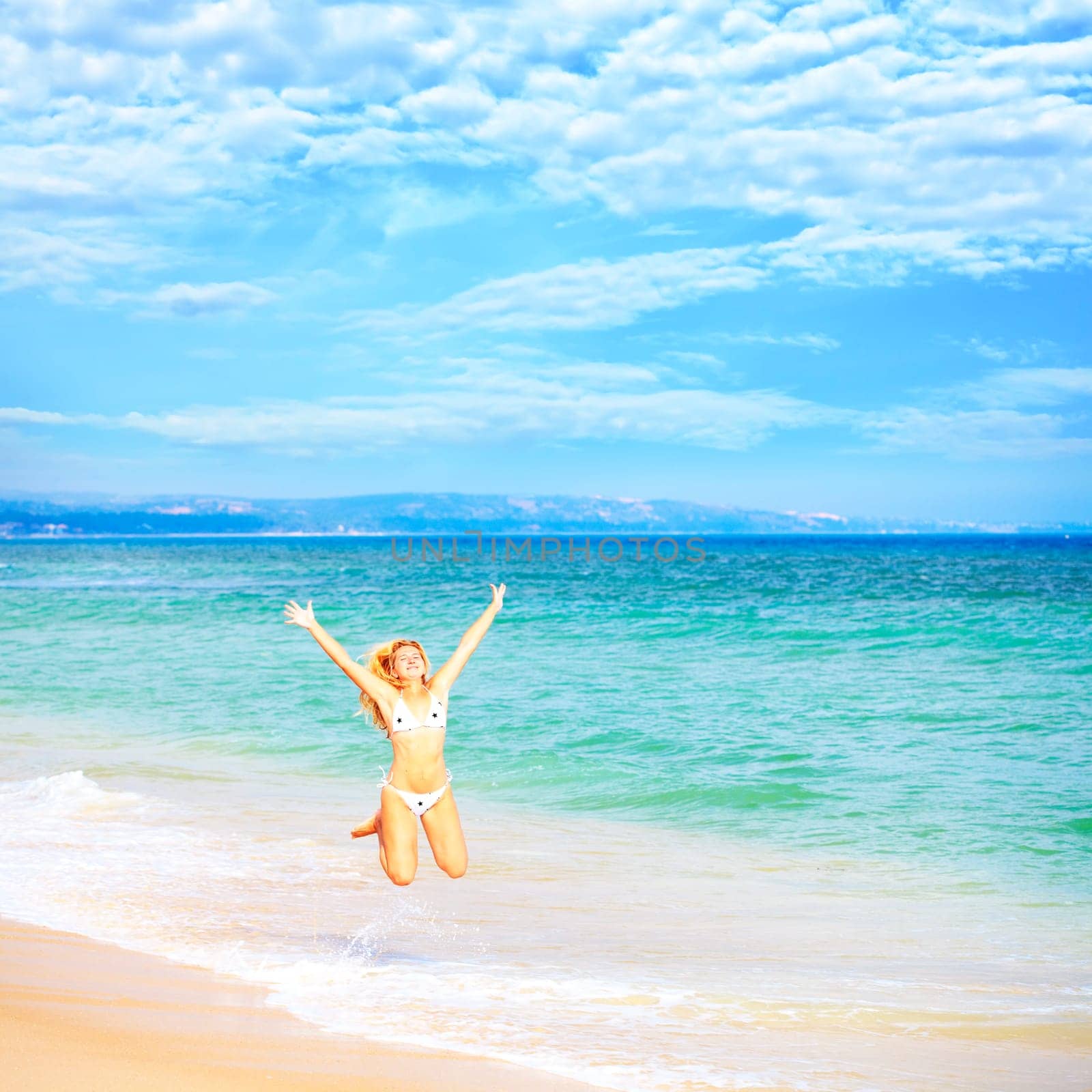 Young woman in bikini  jumping on the tropical beach