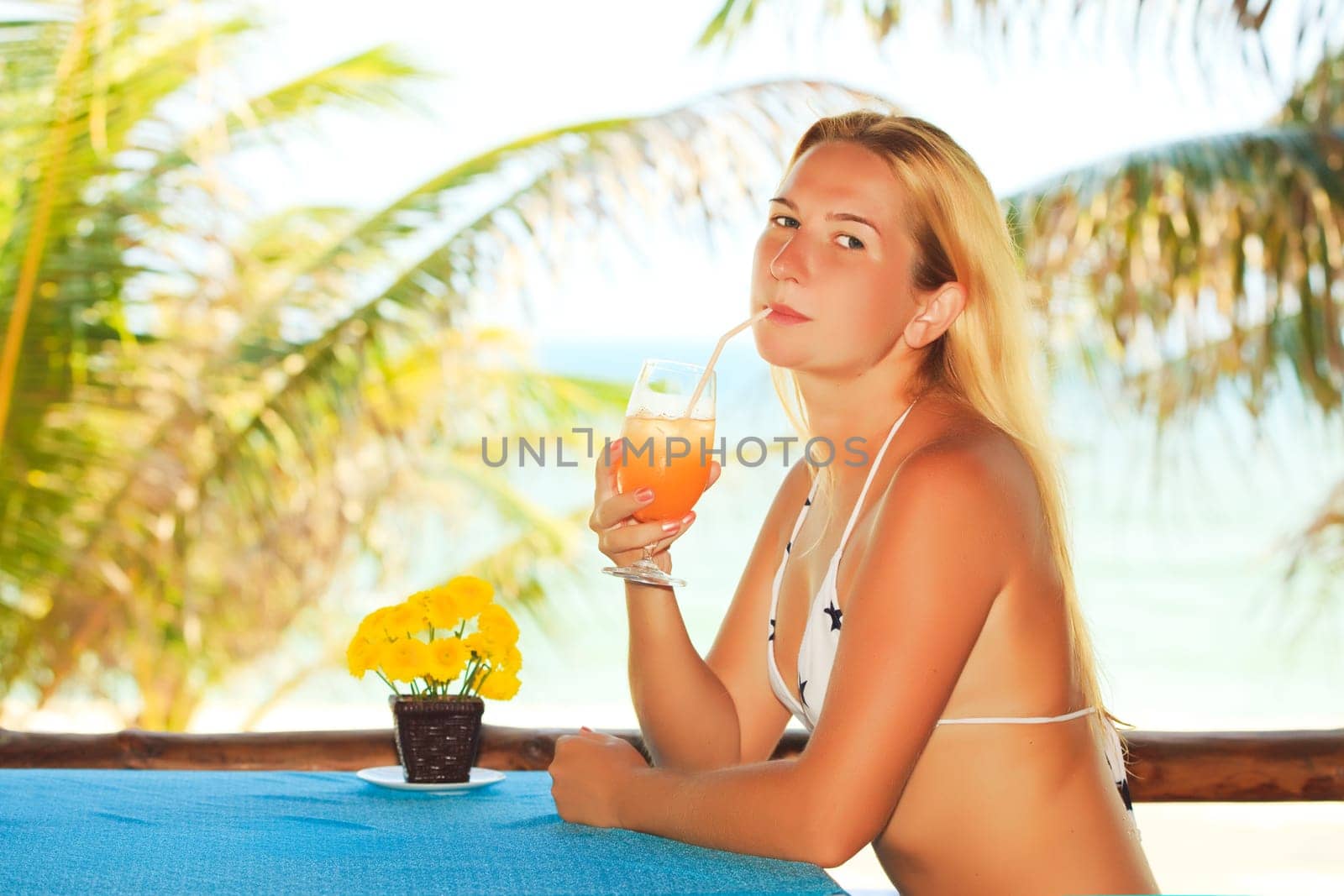 Woman is drinkin juice at the beach restaurant