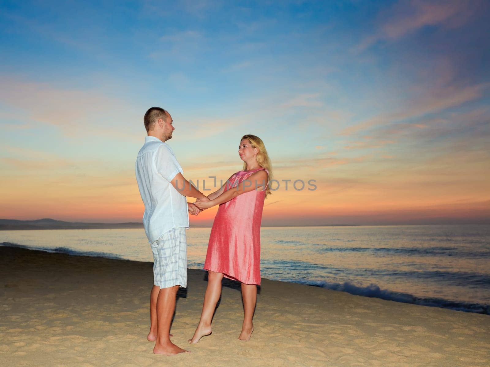 Romantic couple on the beach at sunrise time.