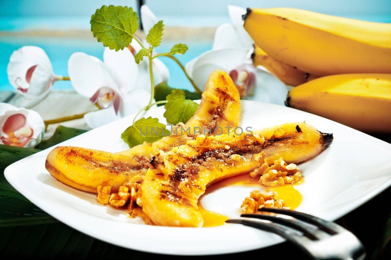 Delicious golden brown grilled banana and walnut dessert served on a white platter