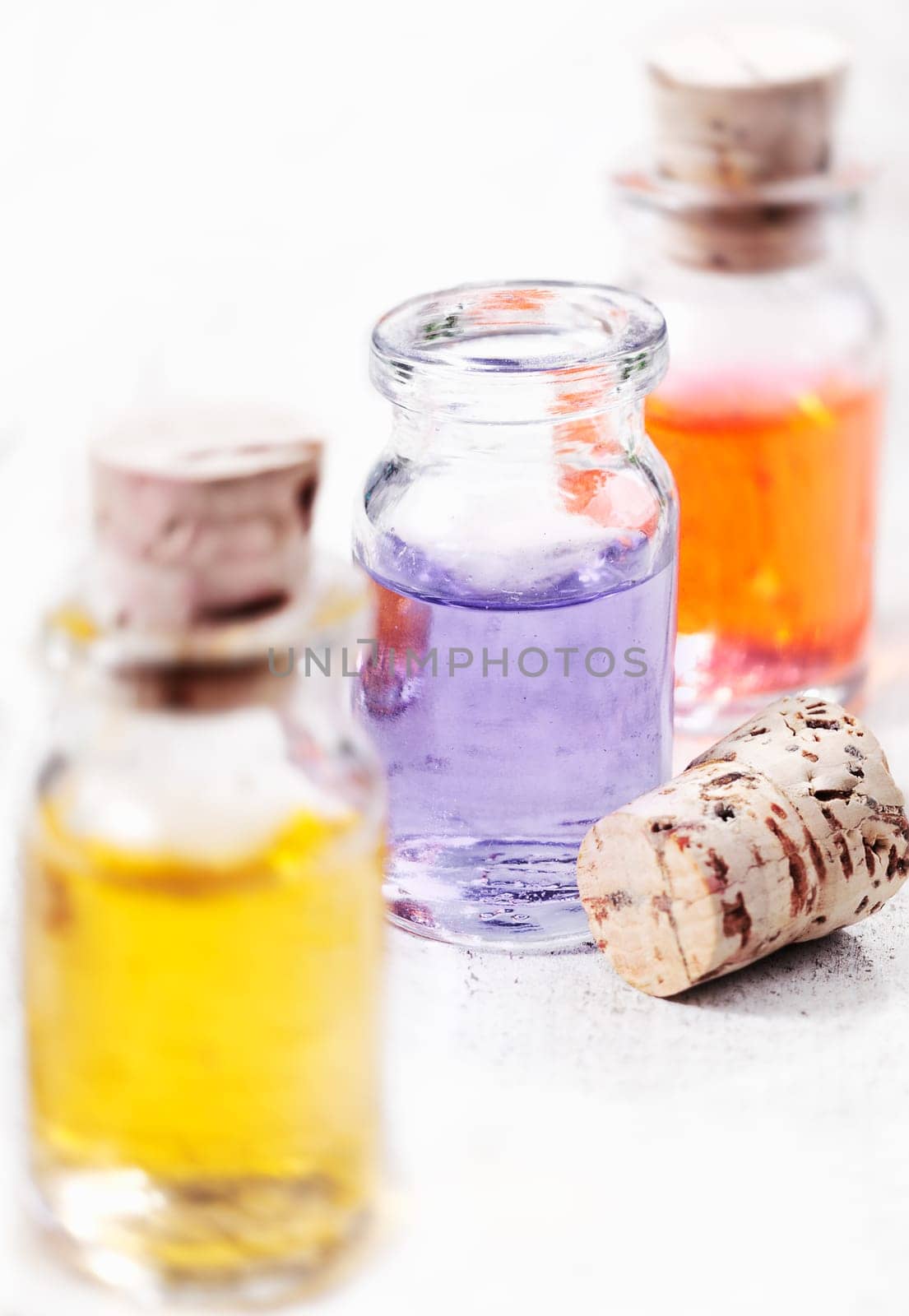Three glass bottles of aromatherapy essential oils ready for a spa treatment with focus to the centre bottle