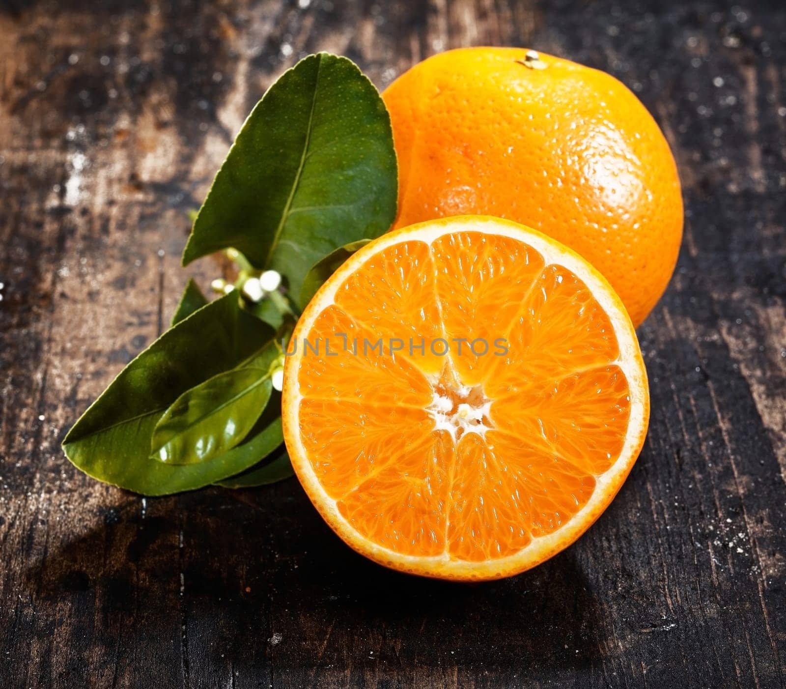 Sliced Orange Fruit with leaves and blossom on an old and vintage rustic wooden background