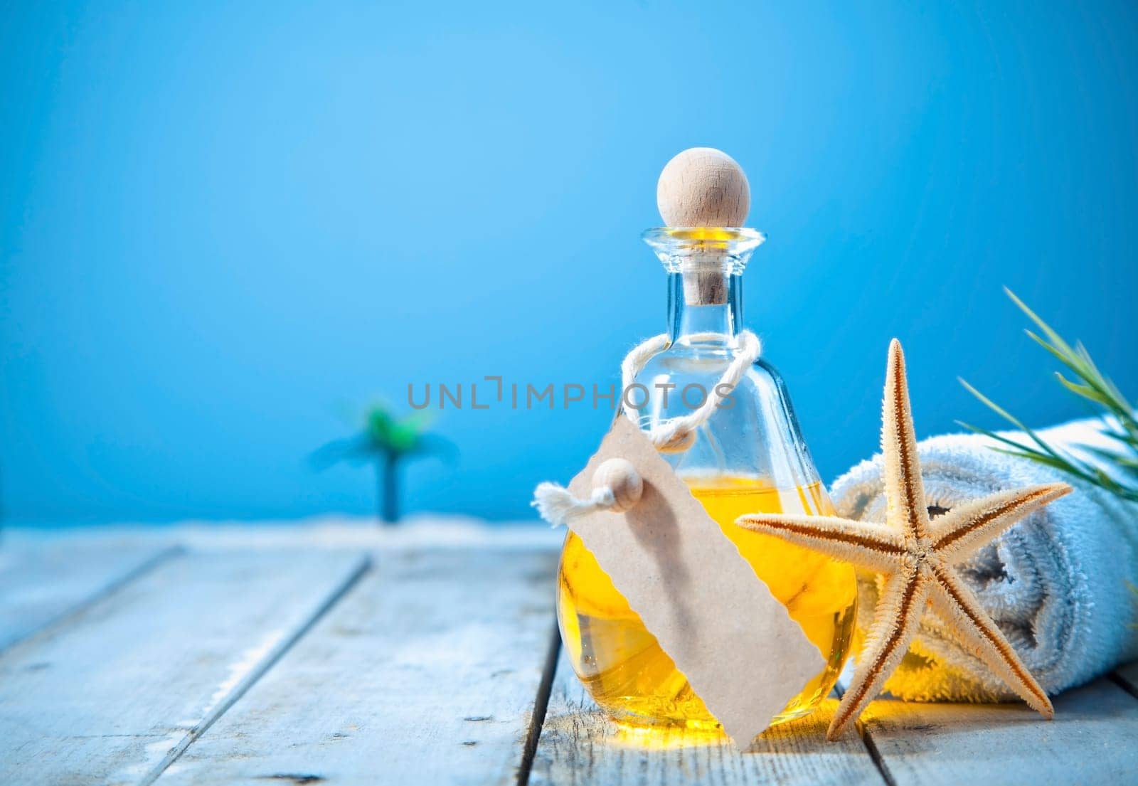 Wellness and rejuvenation with a decanter of golden aromatherapy oil with blank lable on a deck at the seaside