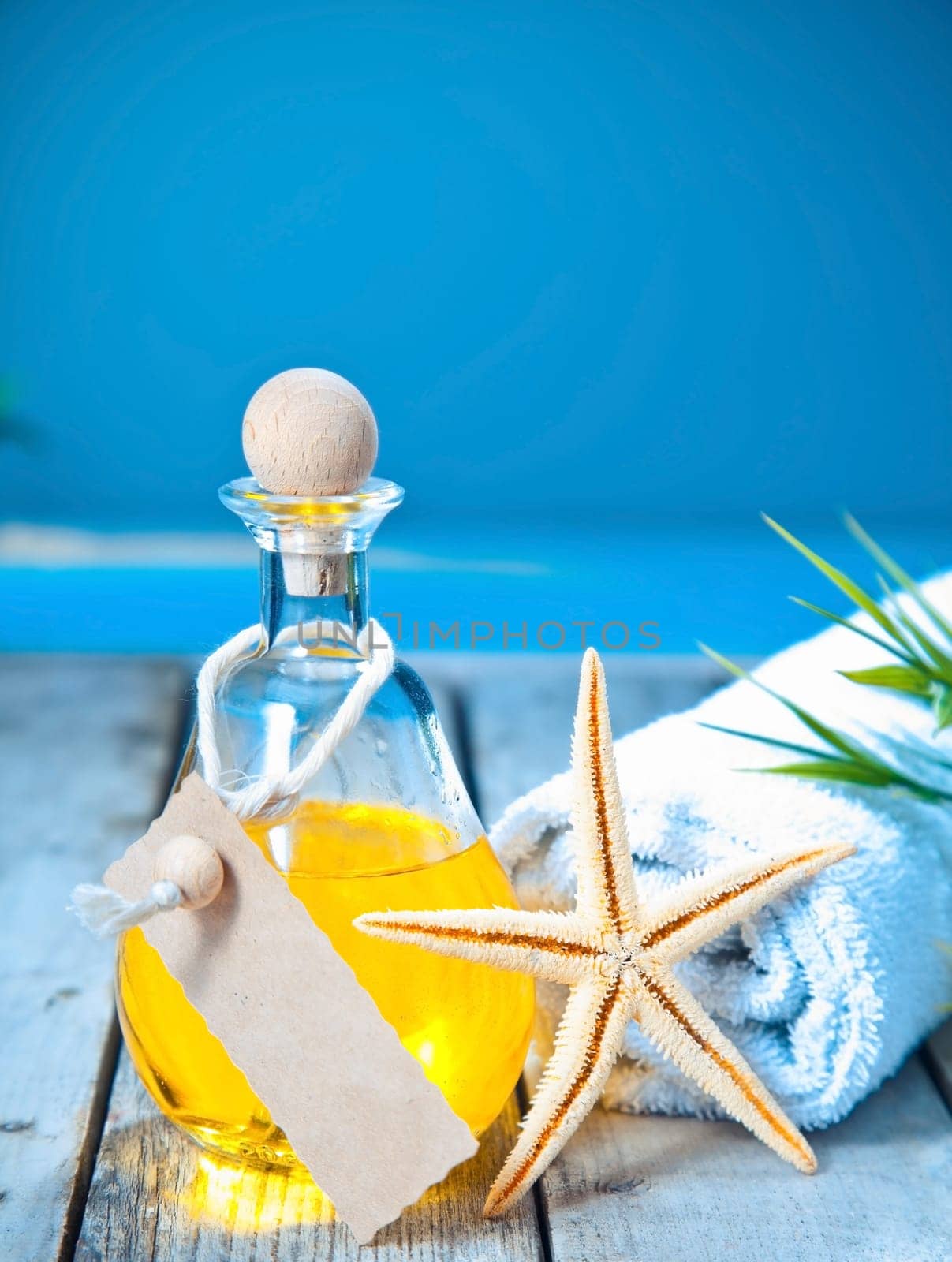 Marine aromatherapy spa treatment with a decanter of golden essential oil and a starfish on a deck overlooking the sea