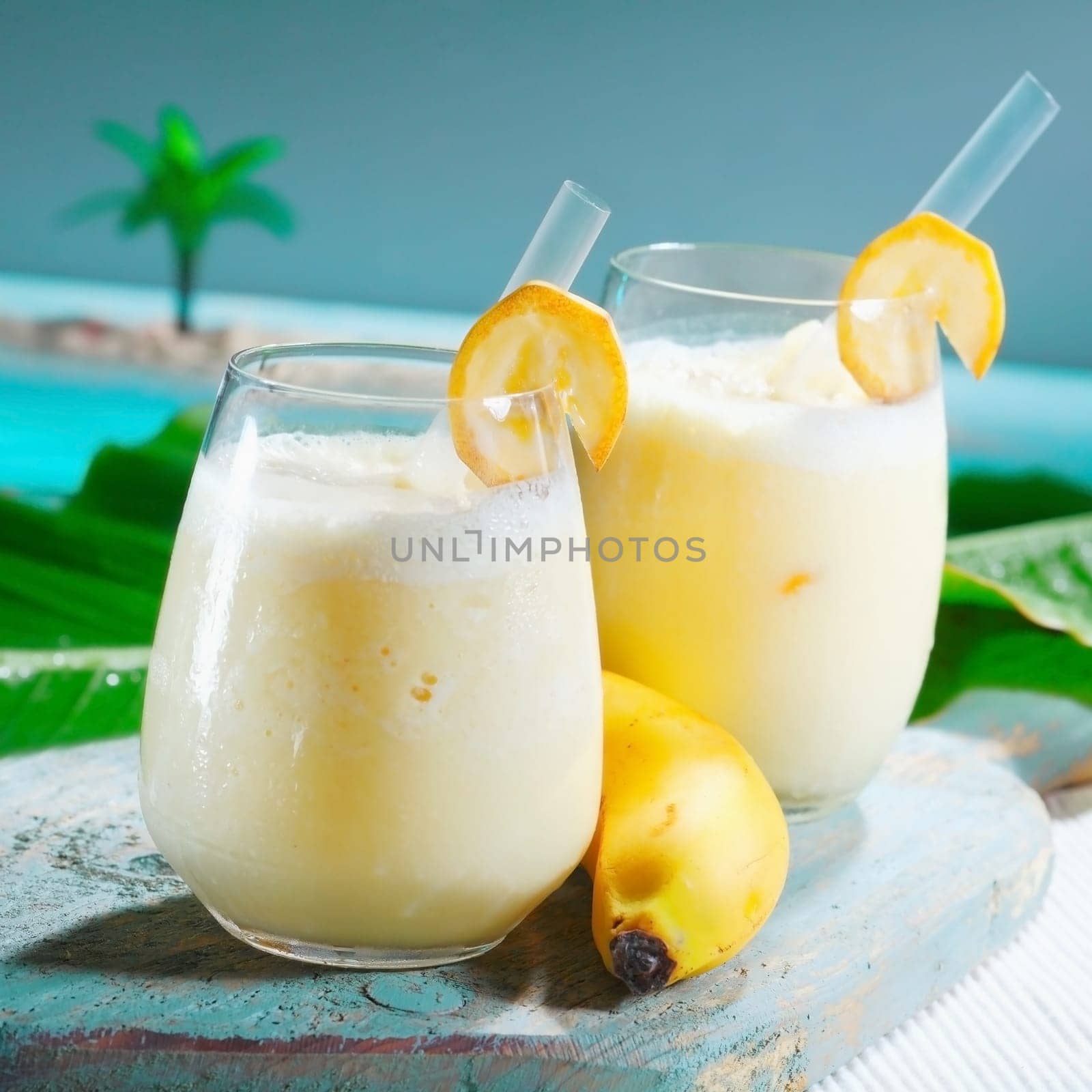 Closeup of two glasses of healthy fruity banana smoothie blended with yoghurt served at a seafront tropical resort