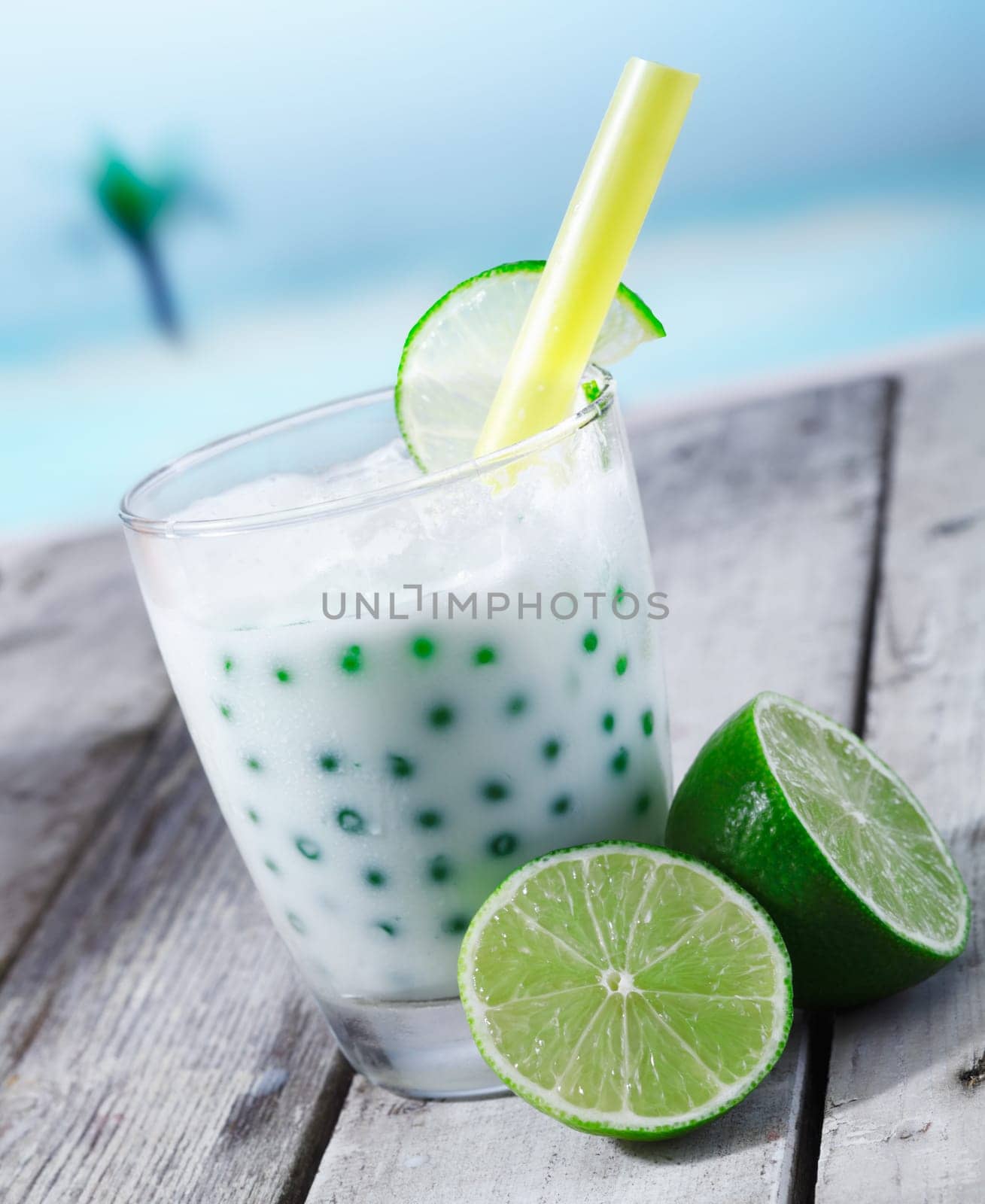 Fresh tapioka pearls tea with lime sirup standing in front of the beach on a wooden plate