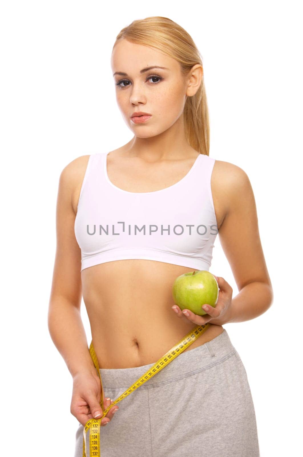 Sporty beautiful girl is measuring her waist on white