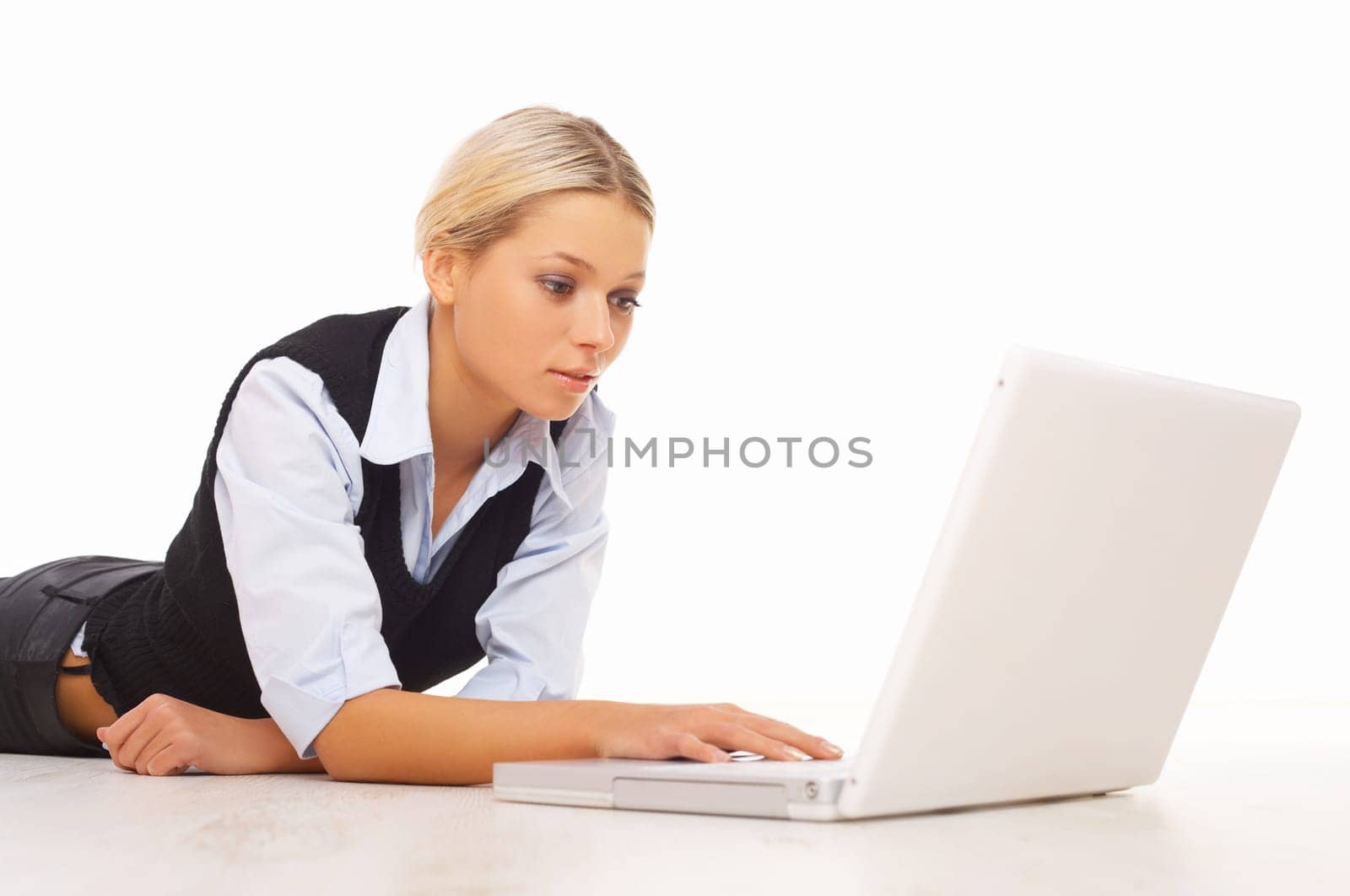 Businesswoman working on her laptop while lying down on the floor