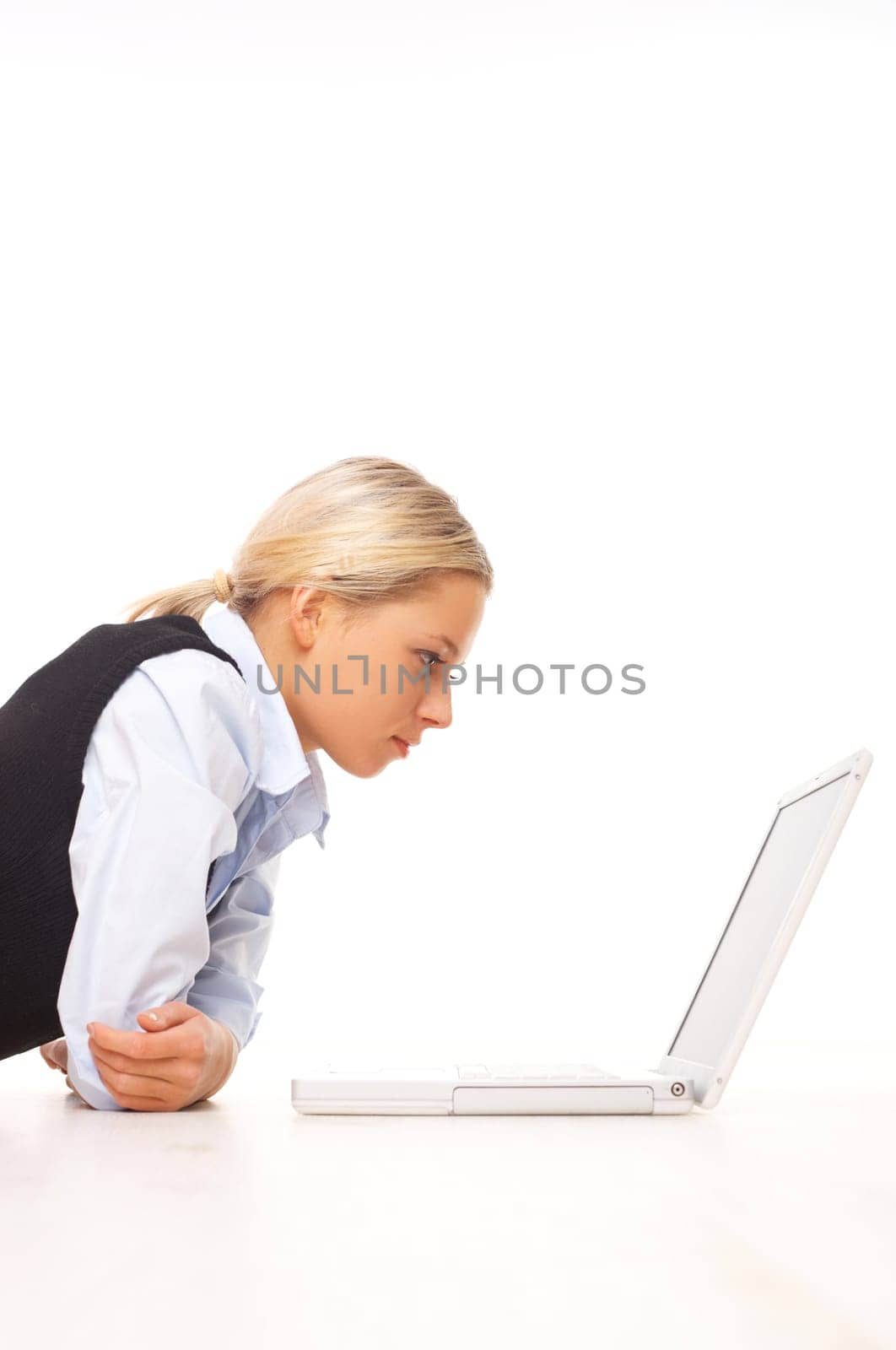 Businesswoman working on her laptop while lying down on the floor