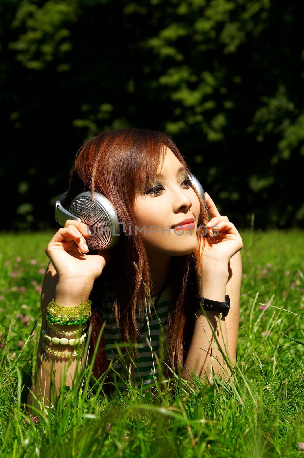Beautiful asian young girl with headphones, listen to music on meadow