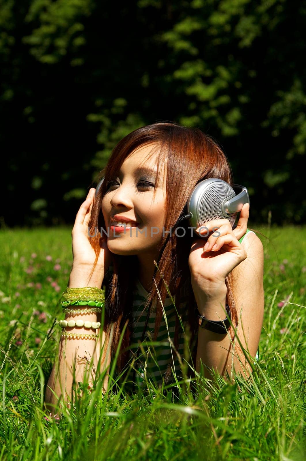 Beautiful asian young girl with headphones, listen to music on meadow